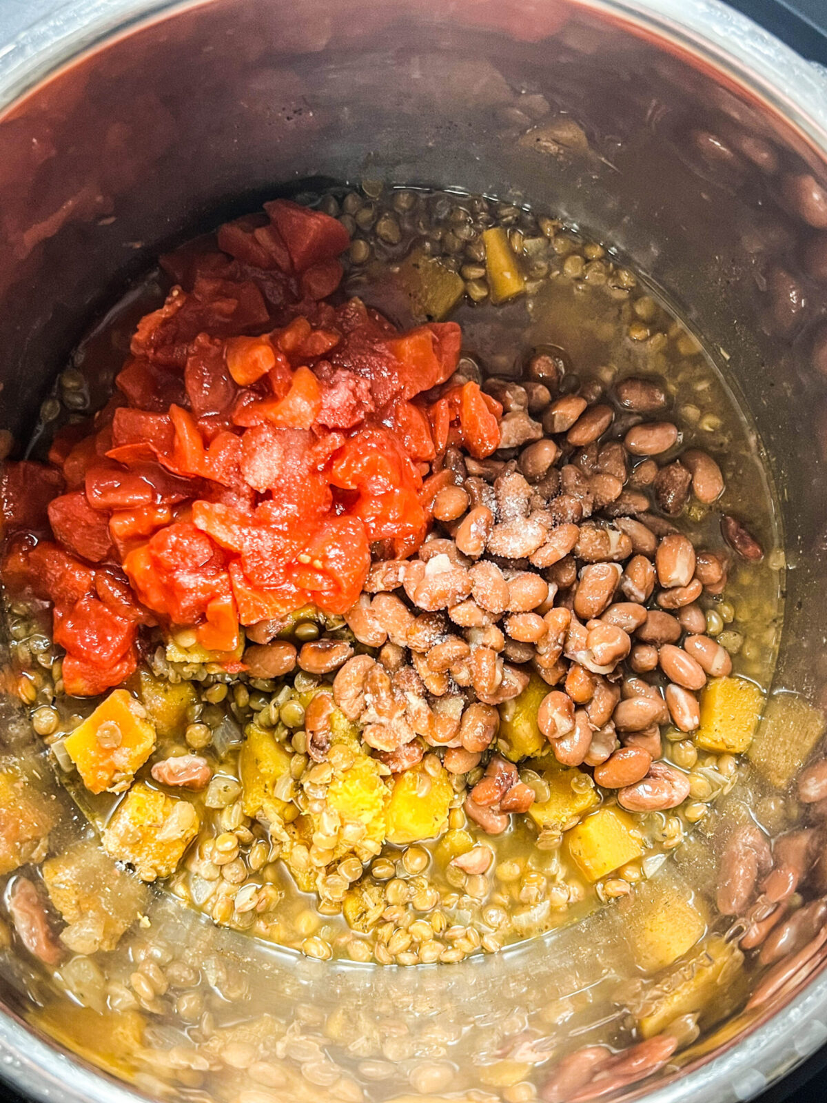Overhead shot of beans, tomatoes and butternut squash in a pot. 
