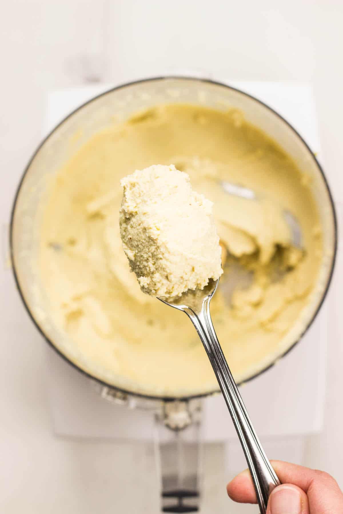 Close up of a spoonful of Cashew Cream Cheese just scooped from food processor.