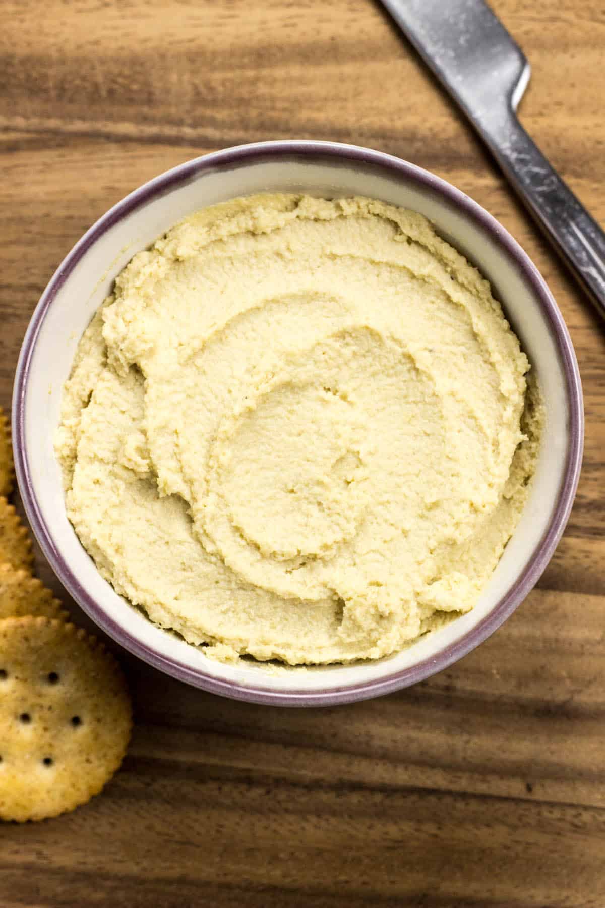 Close up of Cashew Cream Cheese in a small bowl on a wooden background.