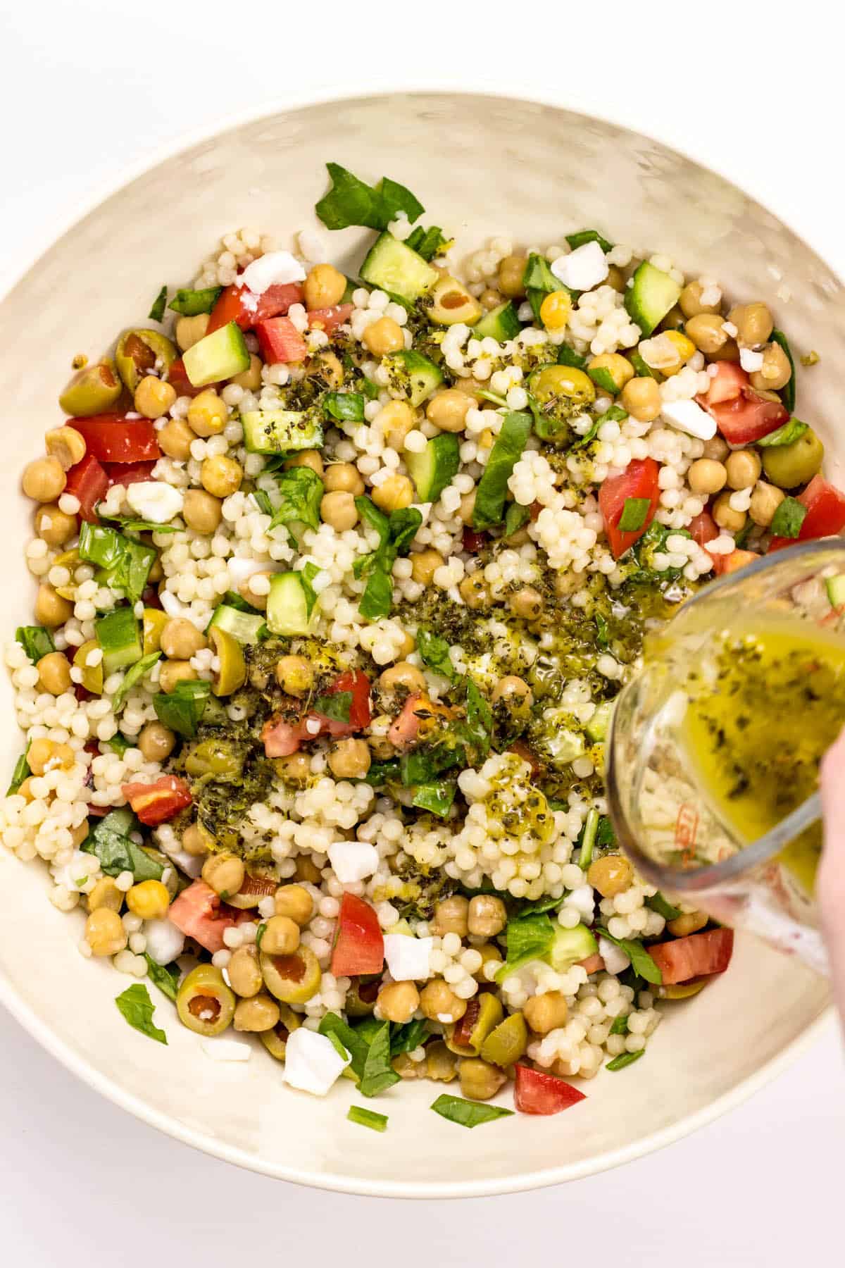 Over head view of dressing being poured onto Vegan Mediterranean Couscous Salad.