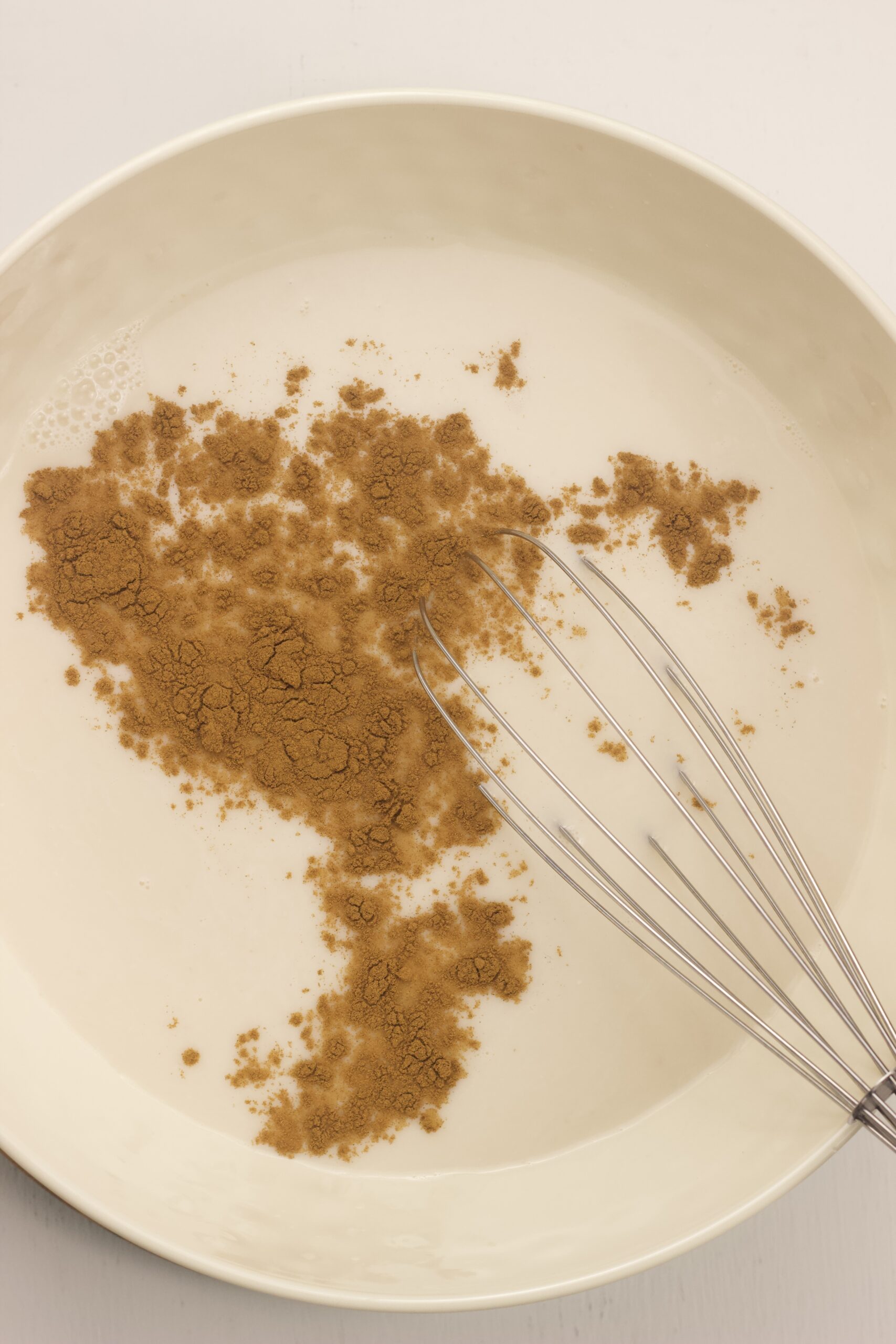 Overhead shot of milk in a bowl with cinnamon before mixing together.