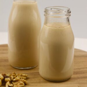 Side view of a bottle of Cinnamon Walnut Milk with a second bottle in background.
