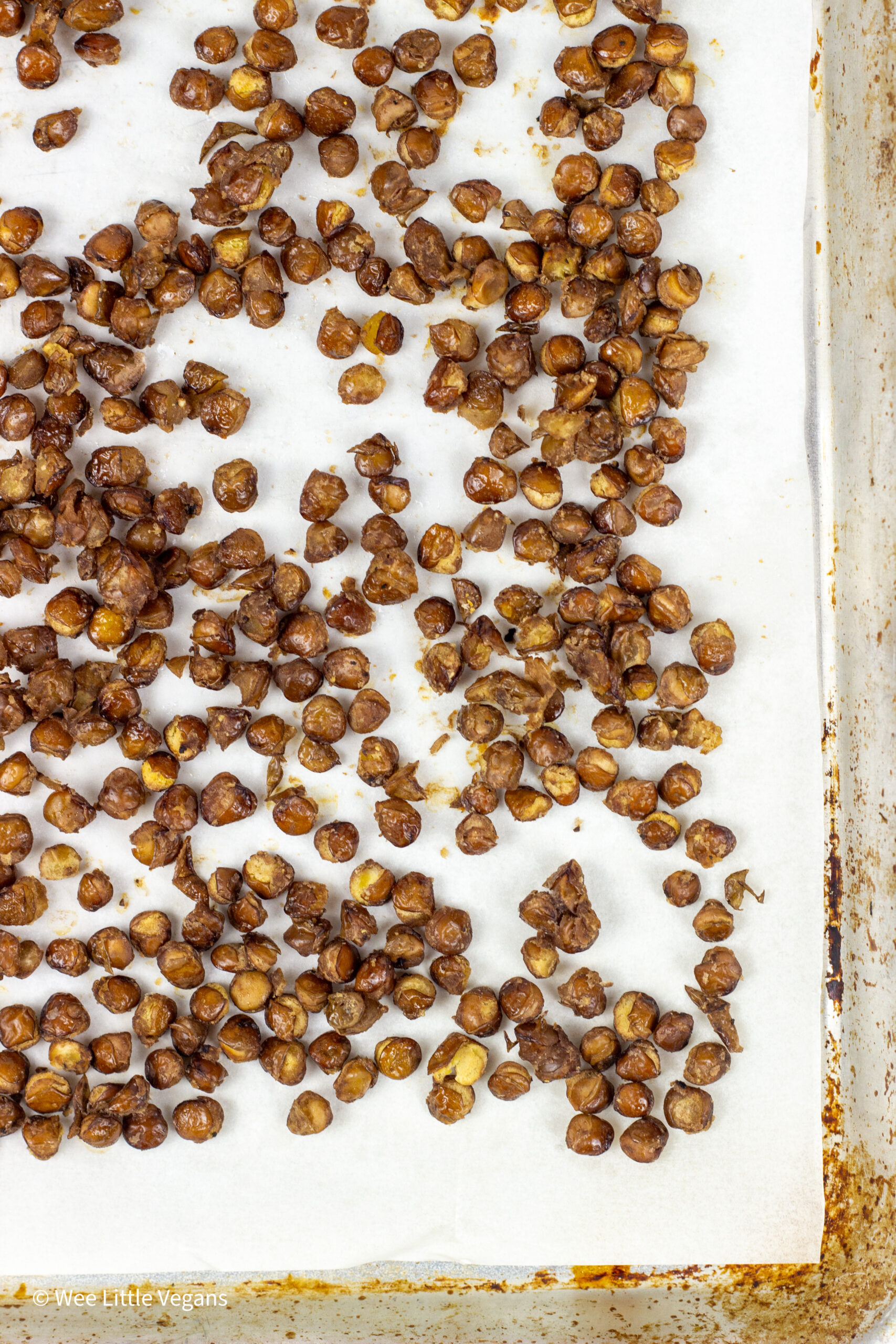 Overhead view of crispy lentils on a parchment lined baking sheet.