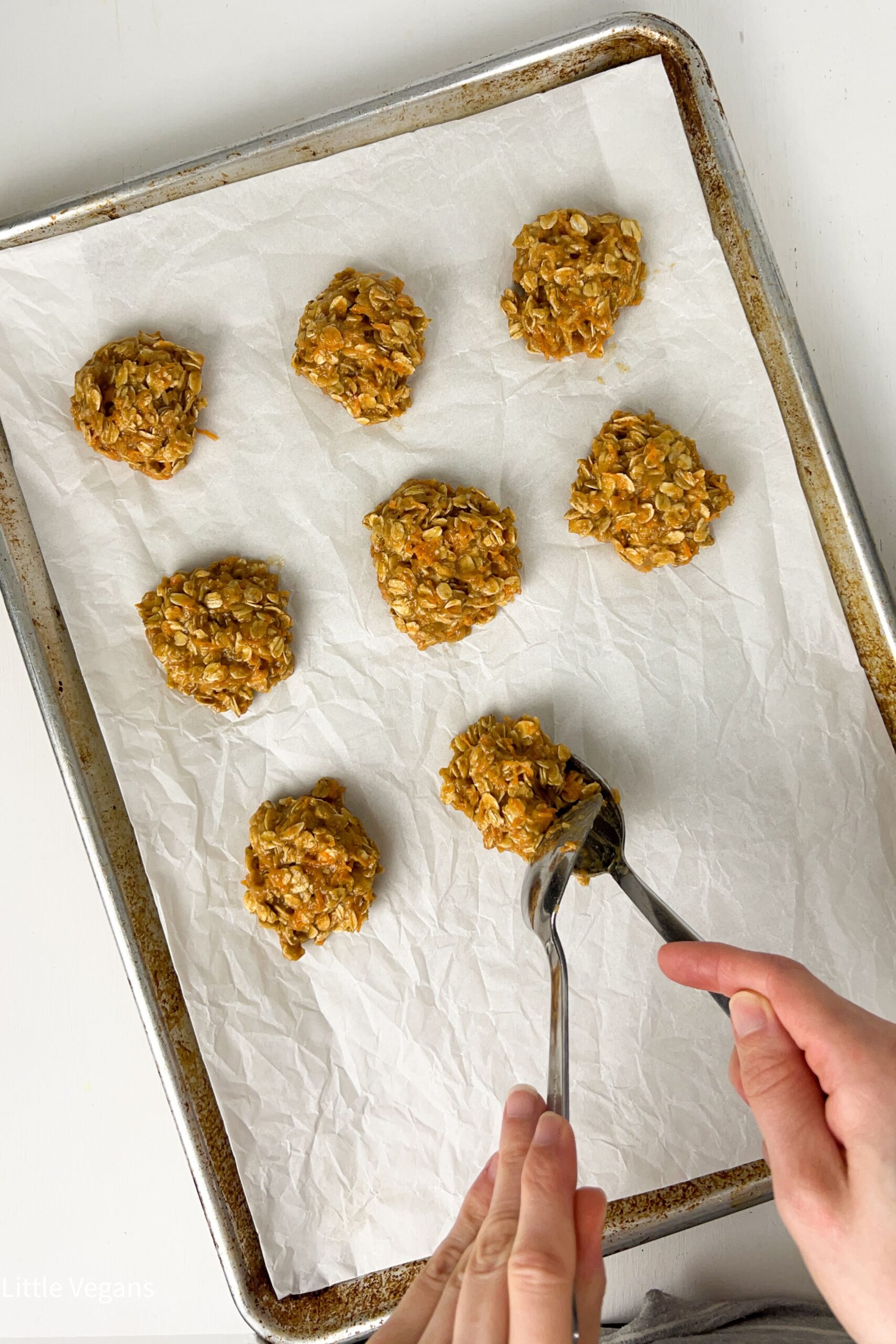 Overhead view of Carrot Oatmeal Cookies being Spooned onto a parchment lined baking sheet.