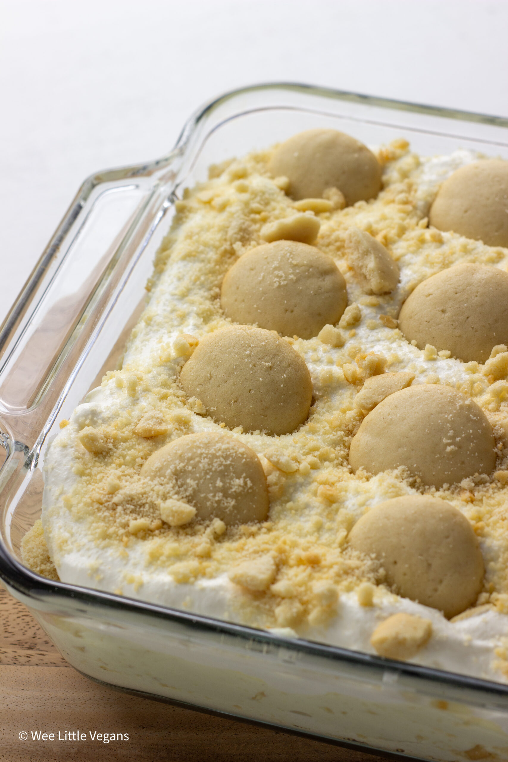 Vegan Banana Pudding in an 8x8 glass baking dish topped with crushed and whole cookies.
