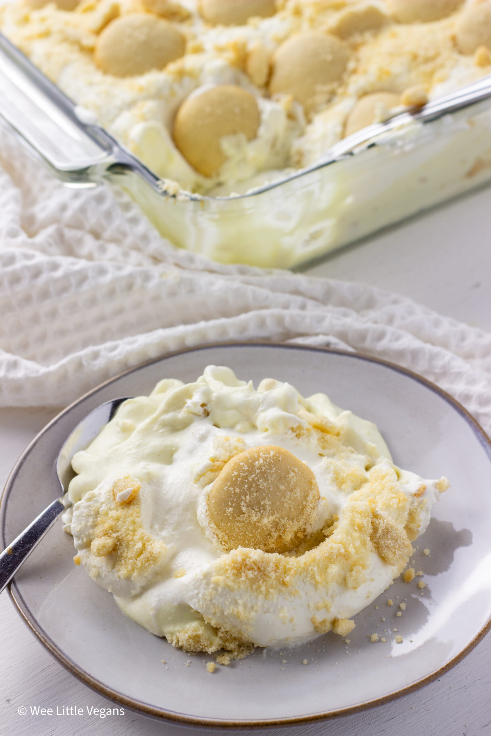 Vegan Banana Pudding on a small plate. The casserole dish of pudding is in the background.