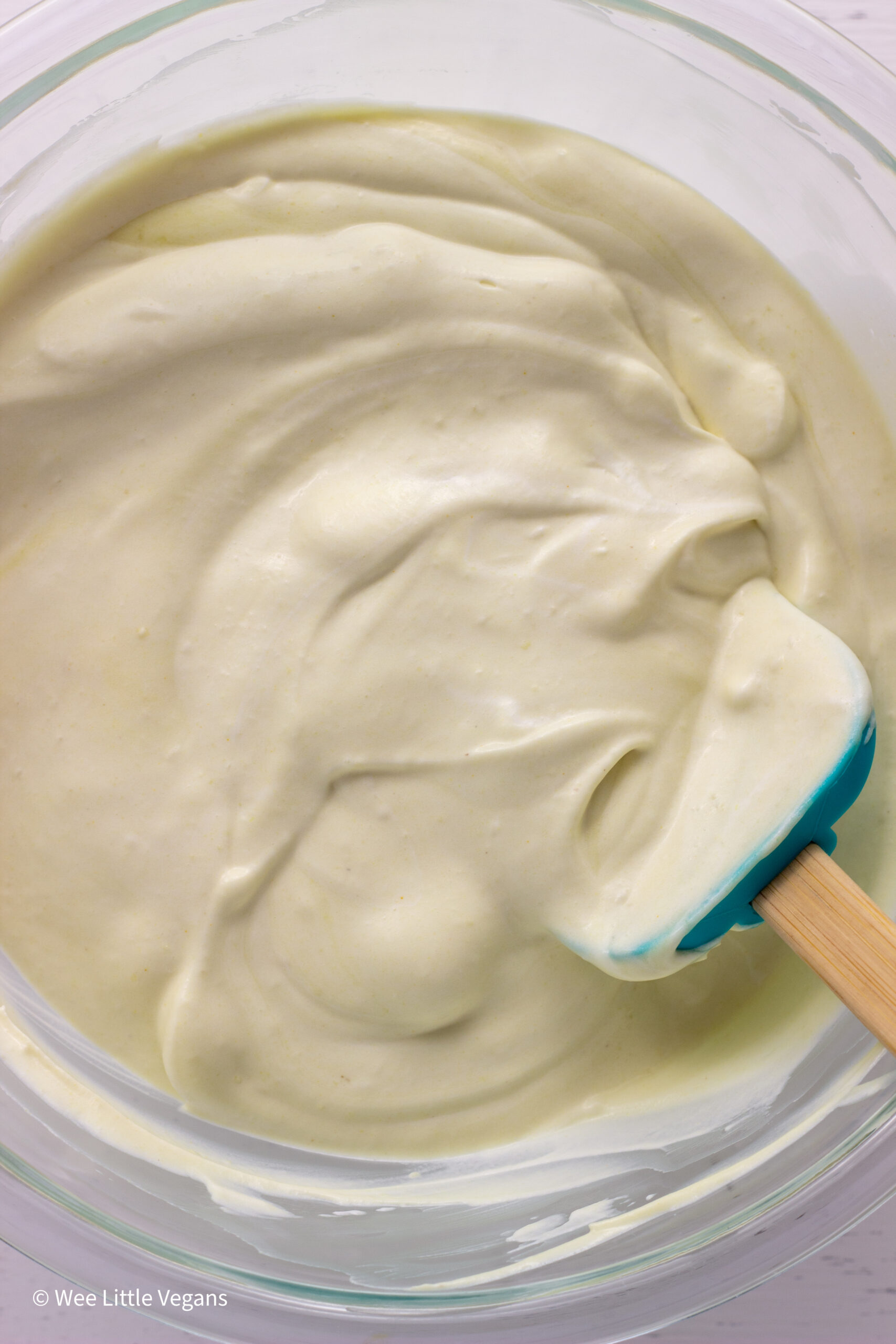 Overhead shot of banana pudding and whipped cream combined in a glass bowl.