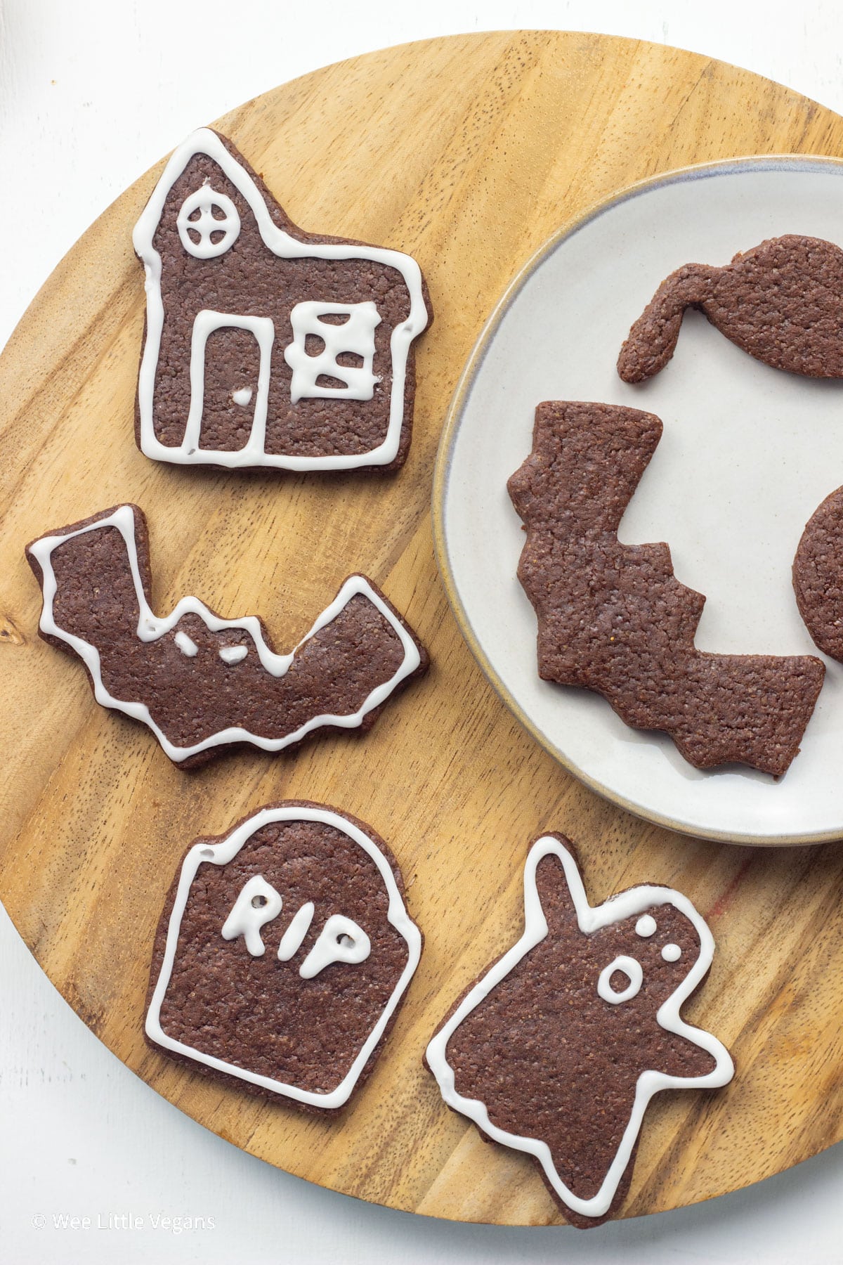 Overhead shot of Halloween themed Spiced Chocolate Cut Out Cookies on a round wooden board.