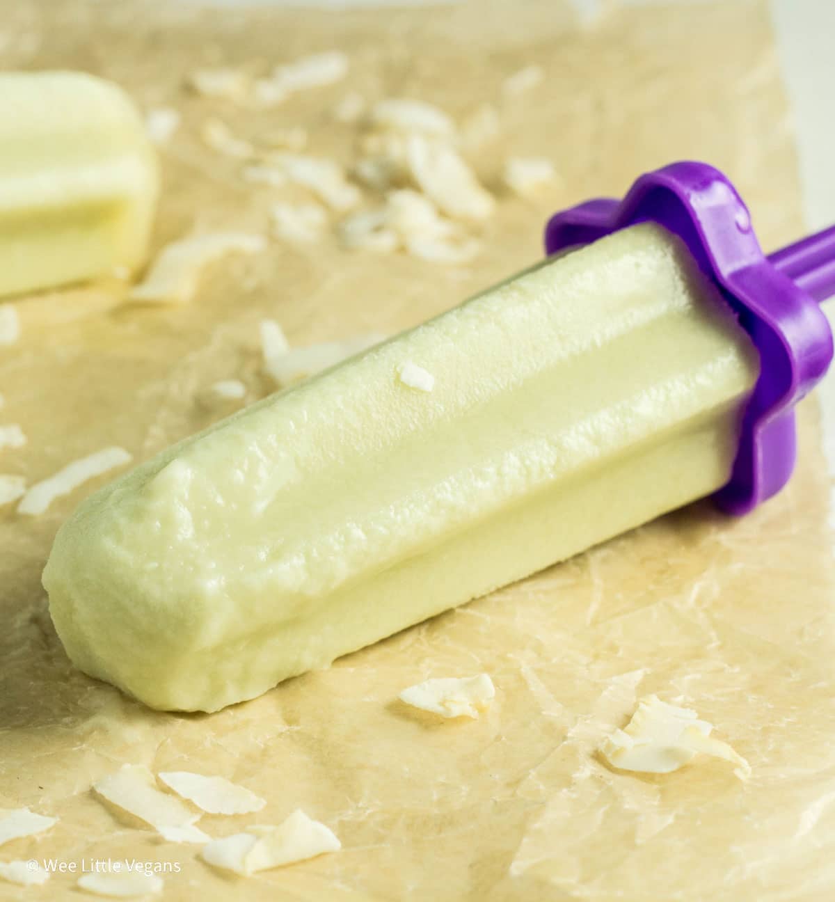 Close up of melty Honeydew Melon Popsicle laying on a parchment paper.