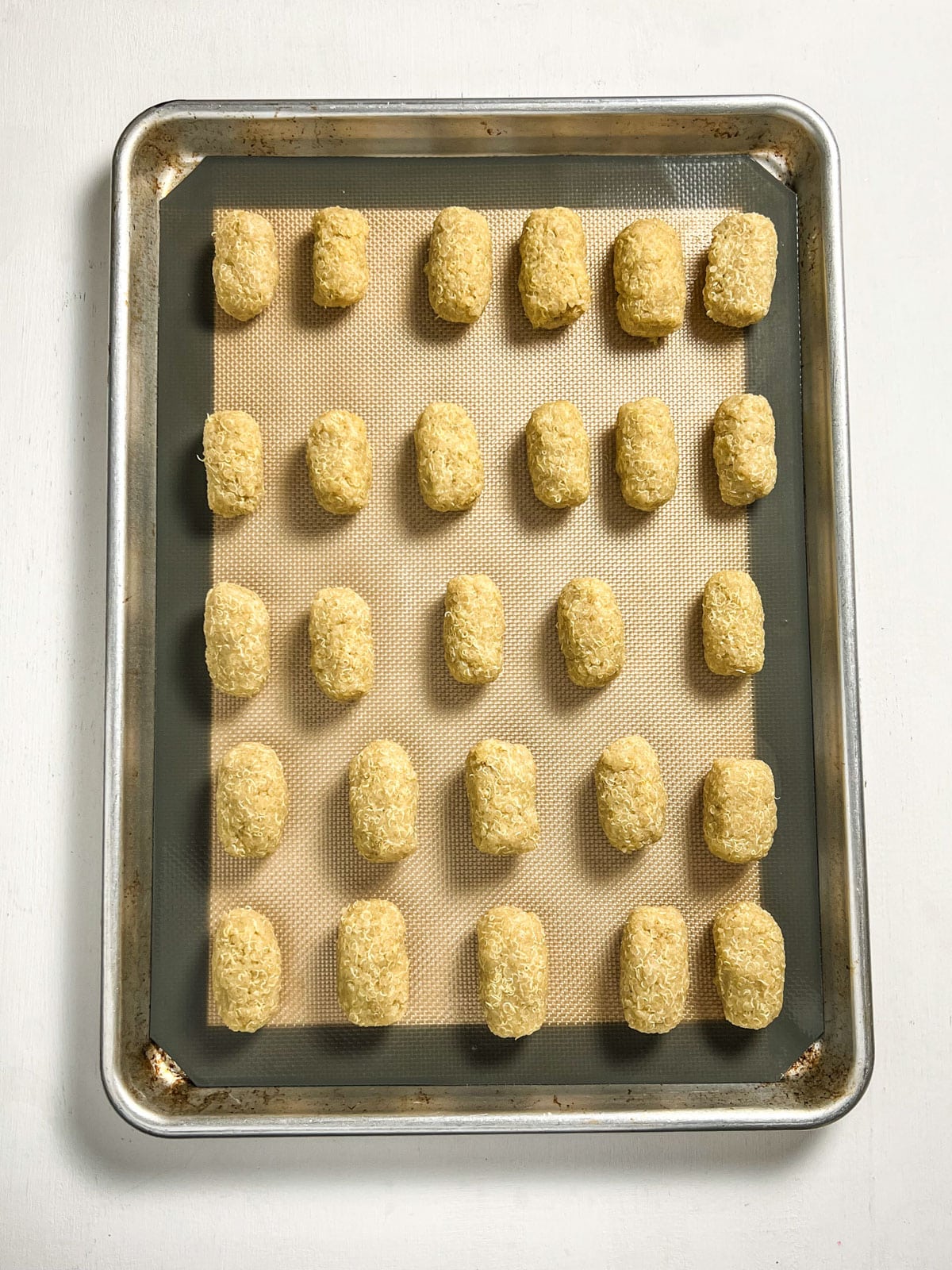 Overhead shot of quinoa tots on a baking sheet before being baked.