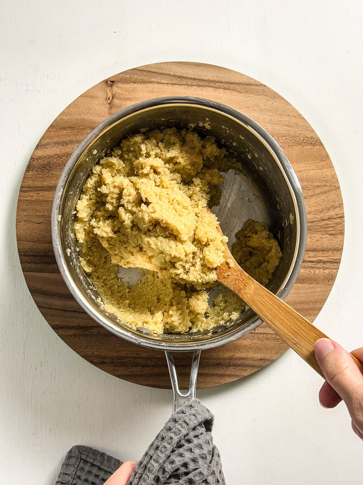 Overhead shot of cooked quinoa stirred into a dough in a sauce pan.