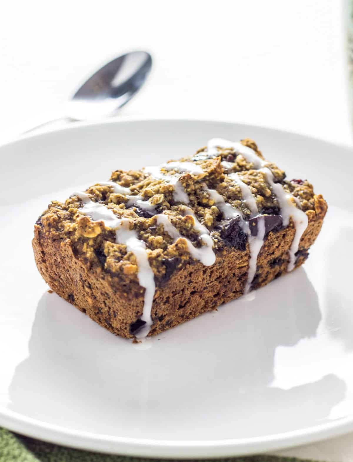 Cherry Vanilla Mini Loaves on a white plate. There is a powdered sugar glaze drizzled over the top of the loaf.