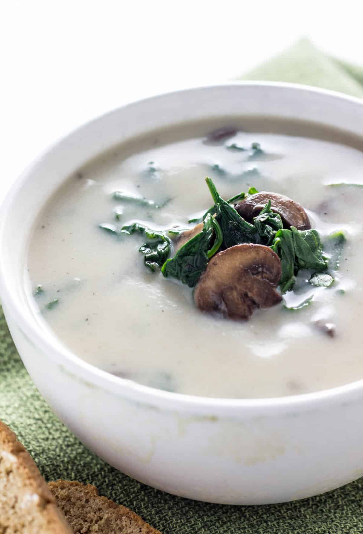 Close up view of Creamy Vegan Mushroom Spinach Soup with sliced sautéed mushrooms and spinach in the center.