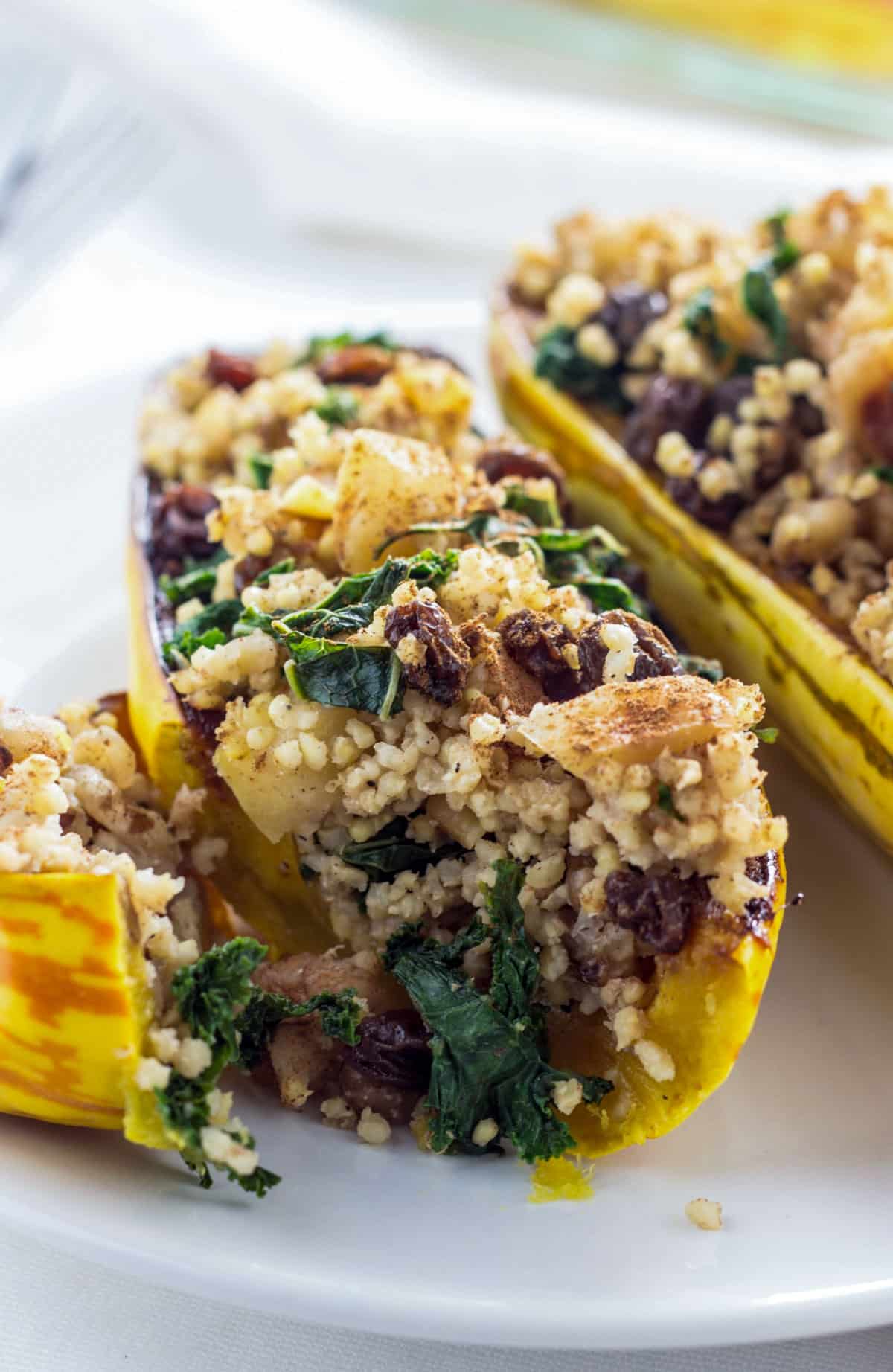 A close up cross section of Millet Stuffed Delicata Squash. There is a millet filling with sautéed apples, onions, kale, walnut and dried fruit.