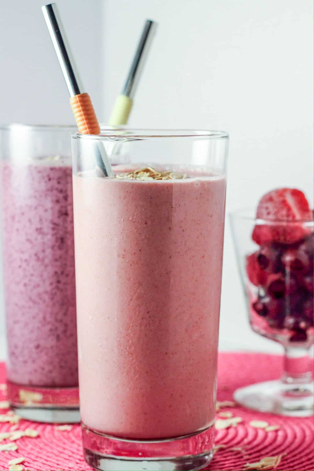 Two glasses of Vegan Fruit 'n Cream Oat Smoothie. One glass is strawberry flavored and the other is blueberry.