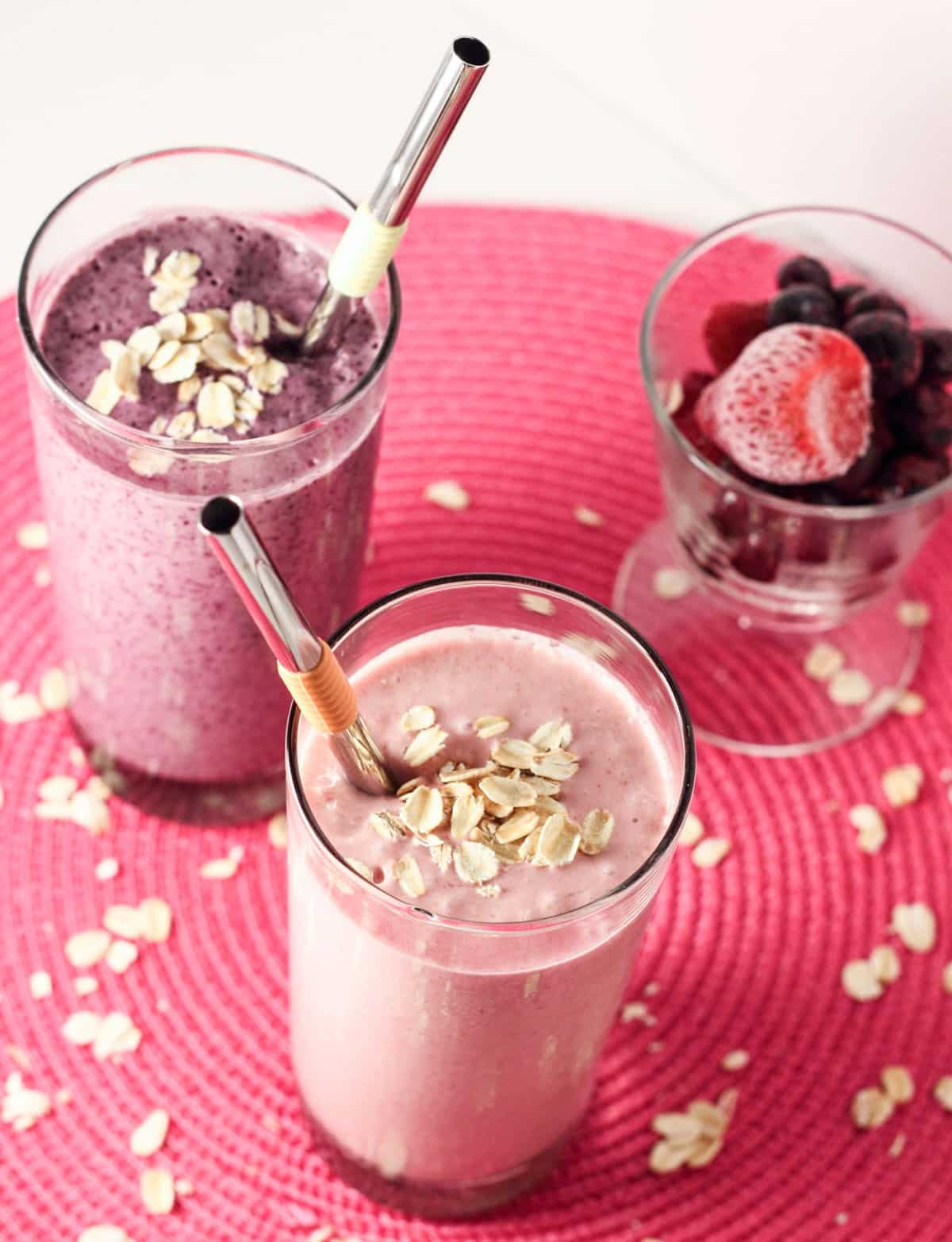 Two glasses of Vegan Fruit 'n Cream Oat Smoothie. One glass is strawberry flavored and the other is blueberry.