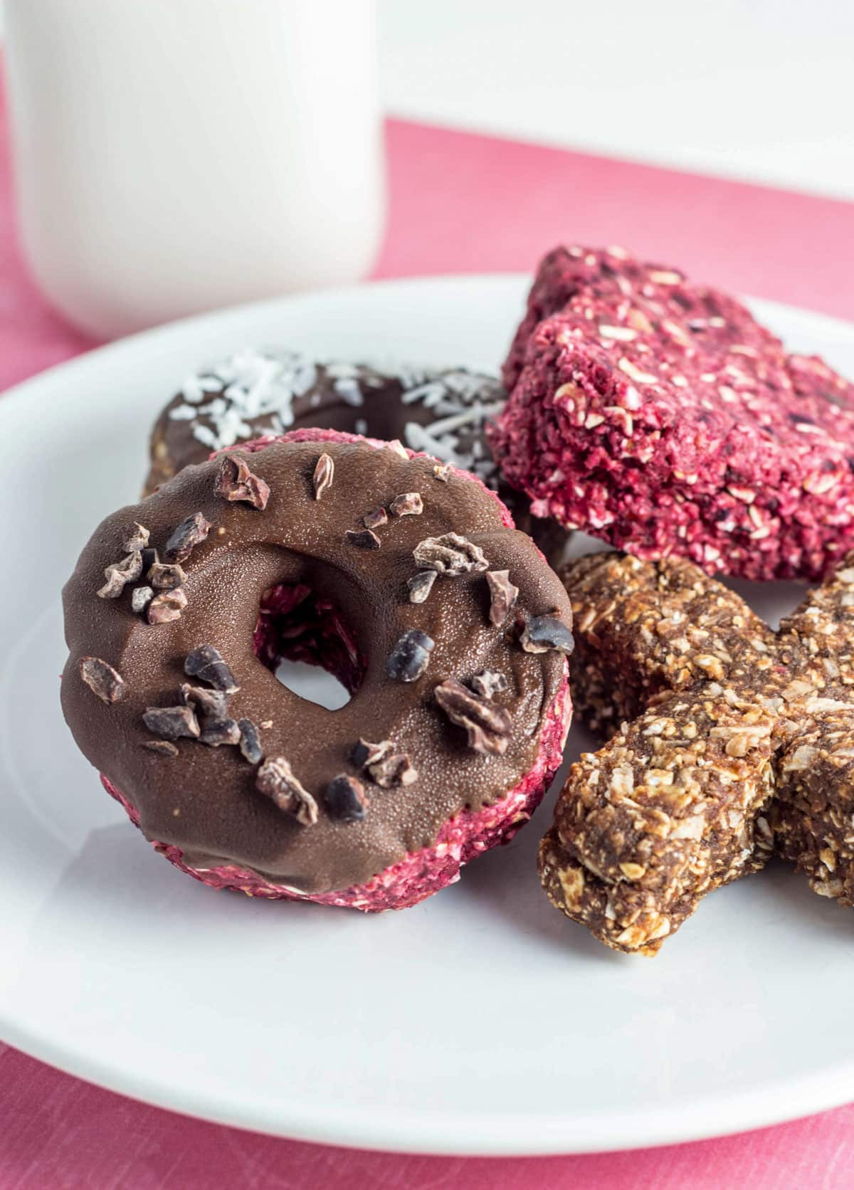 Close up of Vegan Raw Doughnut dipped in chocolate with cacao nibs sprinkled on top.