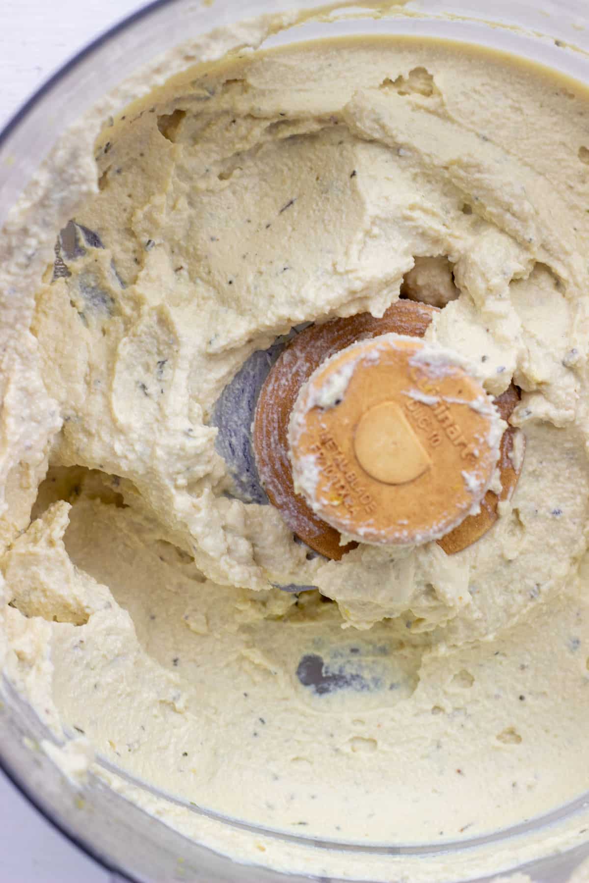 Overhead close up shot of tofu ricotta in the bowl of a food processor.