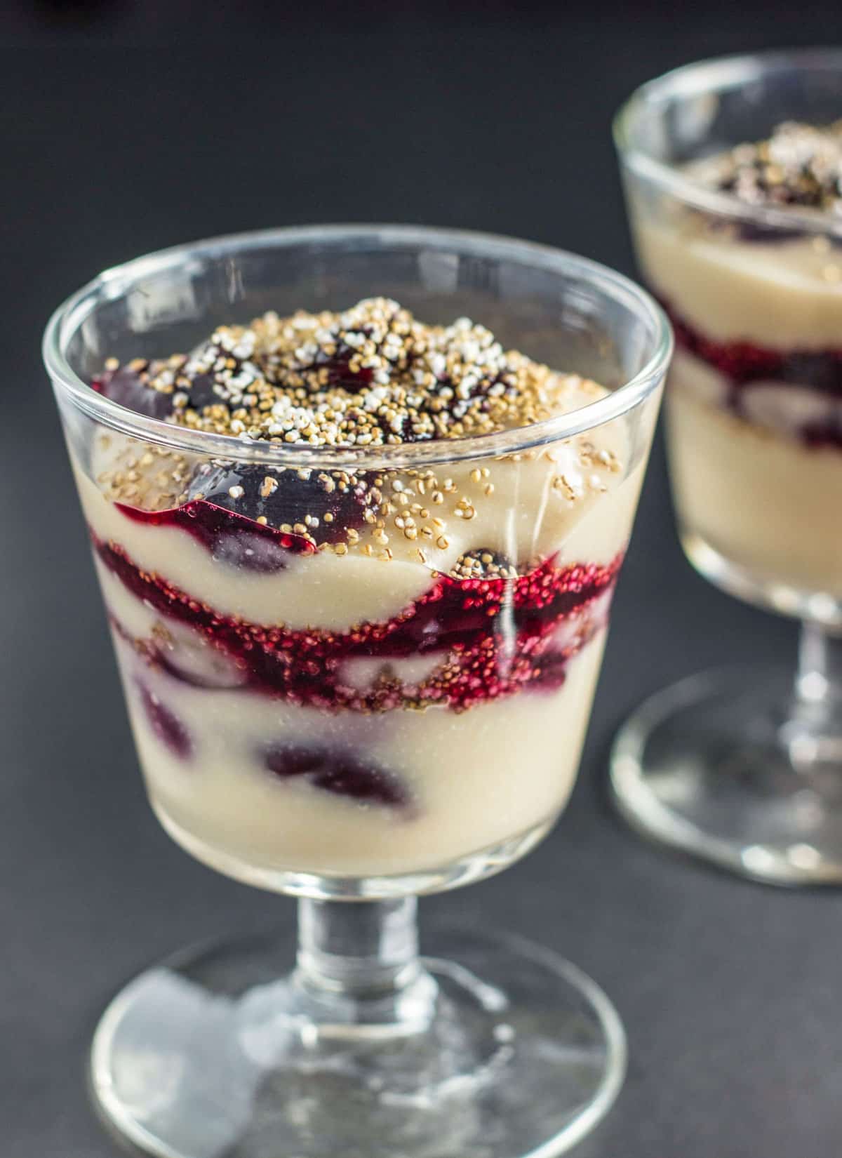 Cherry Maple-Vanilla Pudding Parfait in a glass parfait cup. The pudding is layered with compote and popped amaranth.