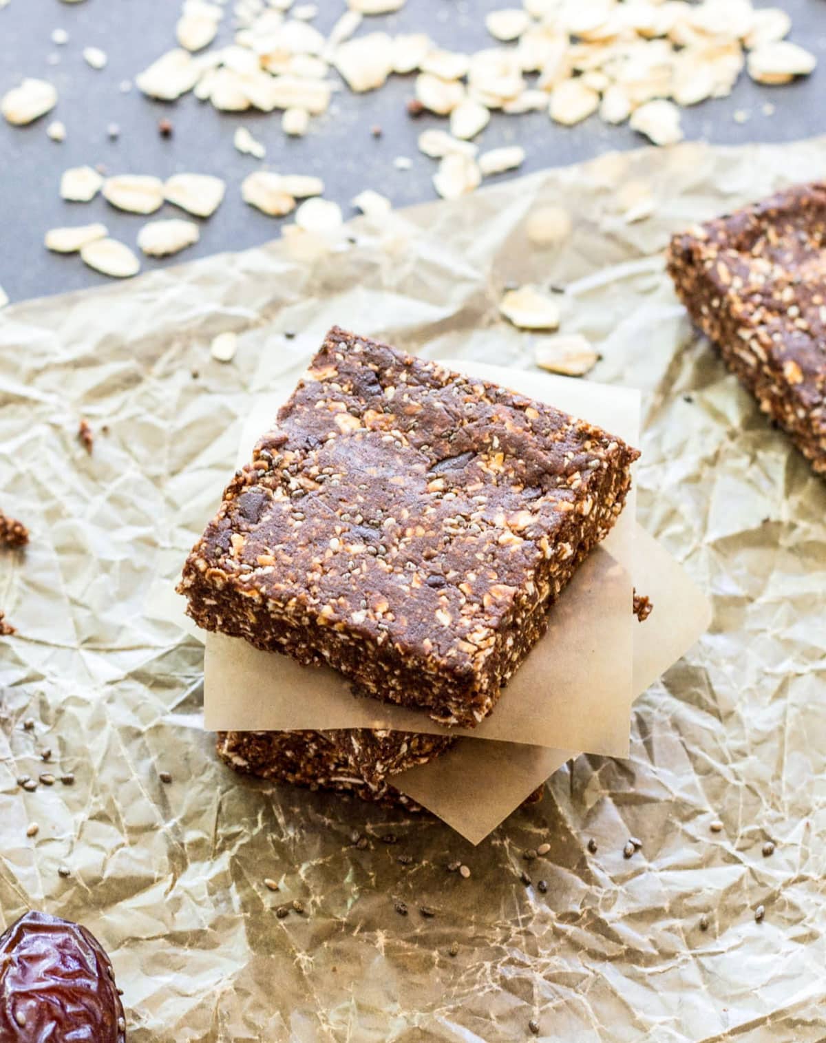 Double Chocolate Mint Oat Squares stacked on a piece of parchment paper. Rolled oats are in the background.