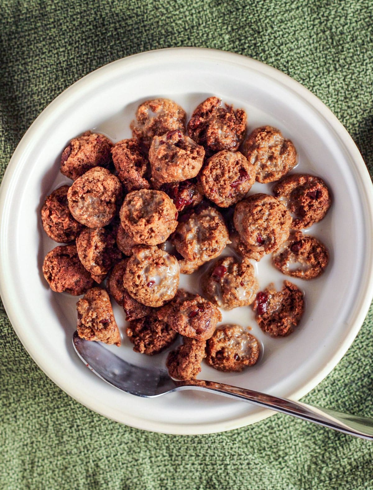 Overhead shot of Healthy Cookie Crisp Cereal in a small bowl with a spoon and non dairy milk.