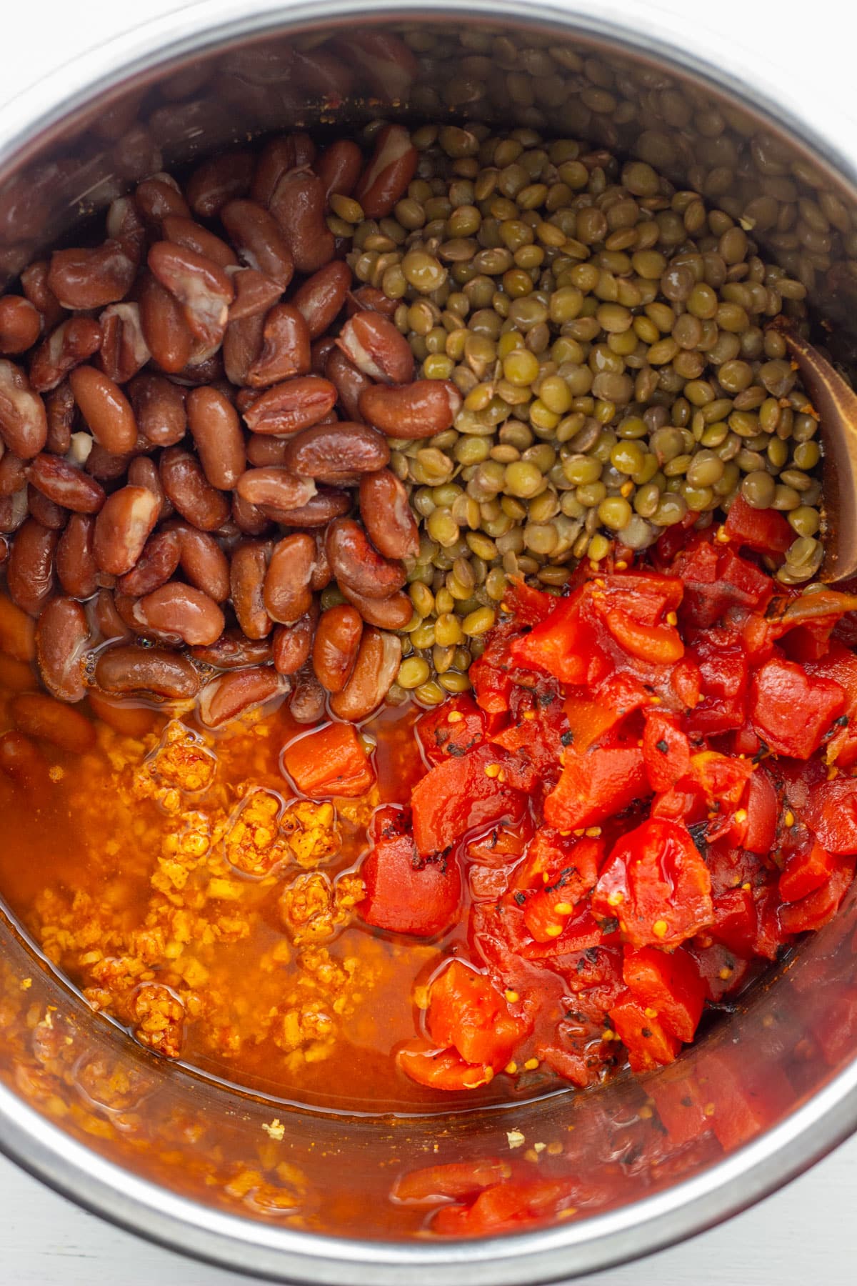 Overhead view of a pot with kidney beans, lentils, diced tomatoes, TVP and water. The ingredients to make TVP Chili.