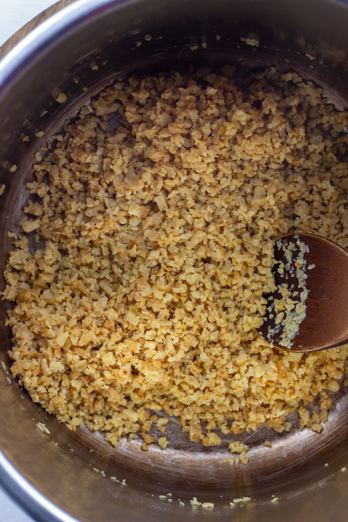 Overhead view of textured vegetable protein sautéing in a pot. This is the first step to making TVP Chili.