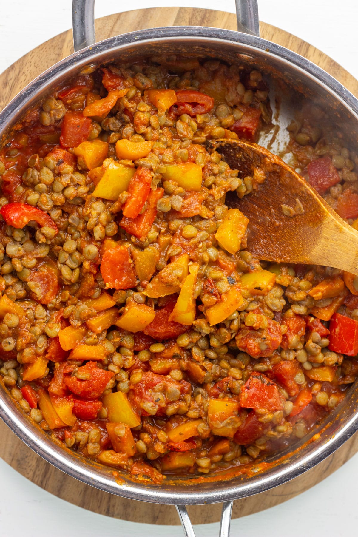 Overhead close up of peppers, lentils and tomatoes cooking in a skillet.