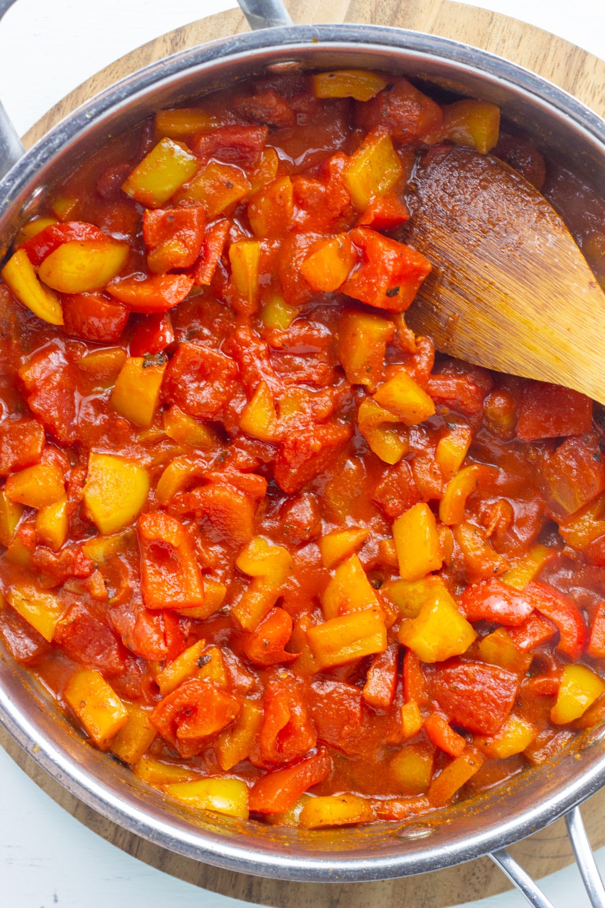 Overhead view of tomatoes and peppers cooking in a skillet.