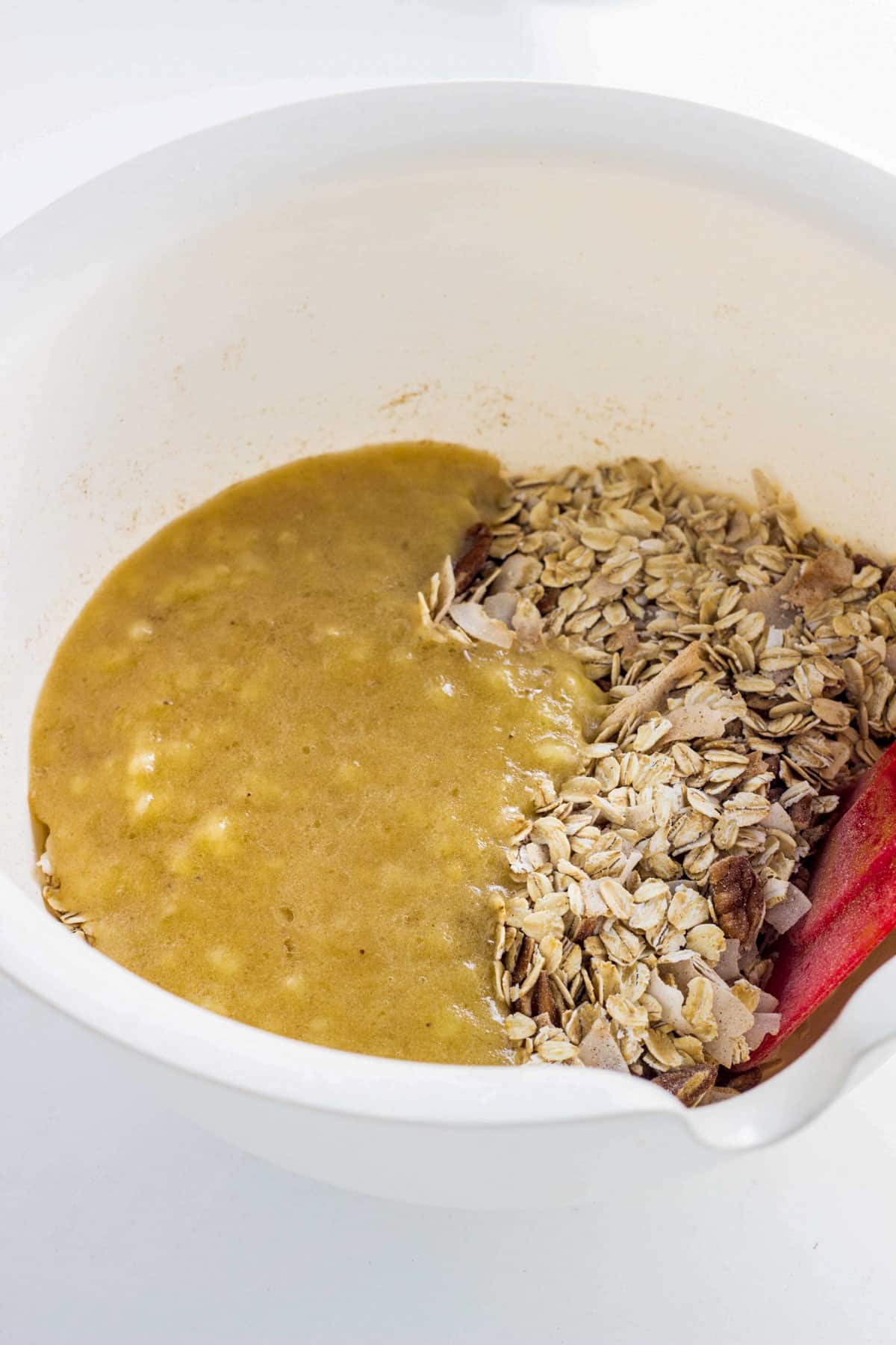 A bowl with oats, pecans and coconut flakes with pureed banana poured over the top.