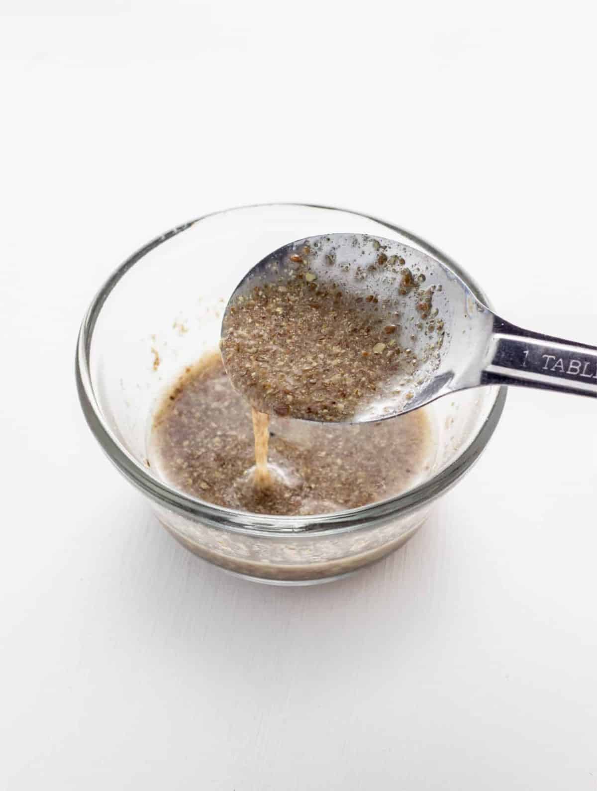 A small bowl of flax egg lifted by a spoon. Image is part of How to Make Flax and Chia Eggs guide.