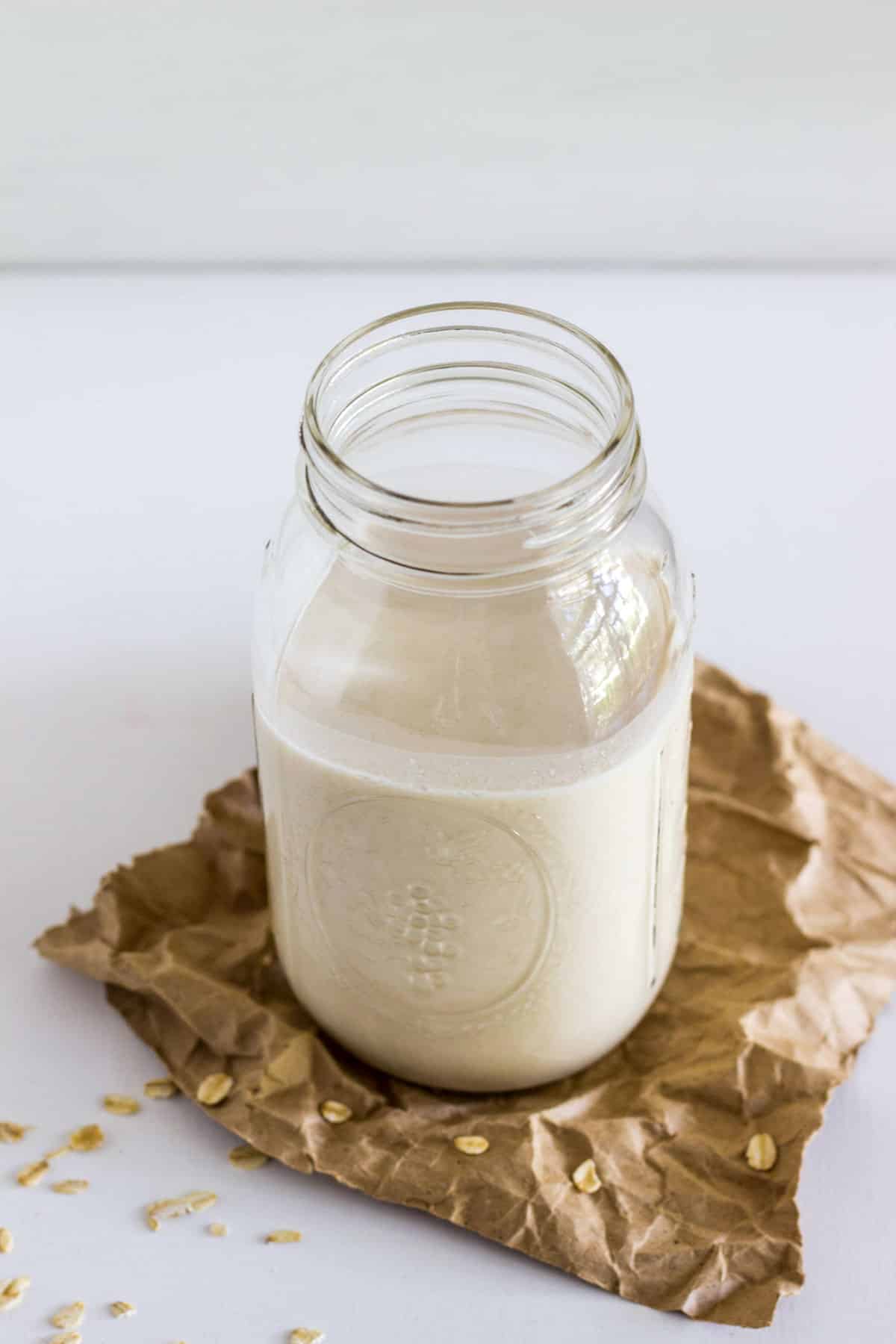 A jar of vanilla oat milk sitting on a crumbled piece of brown paper.