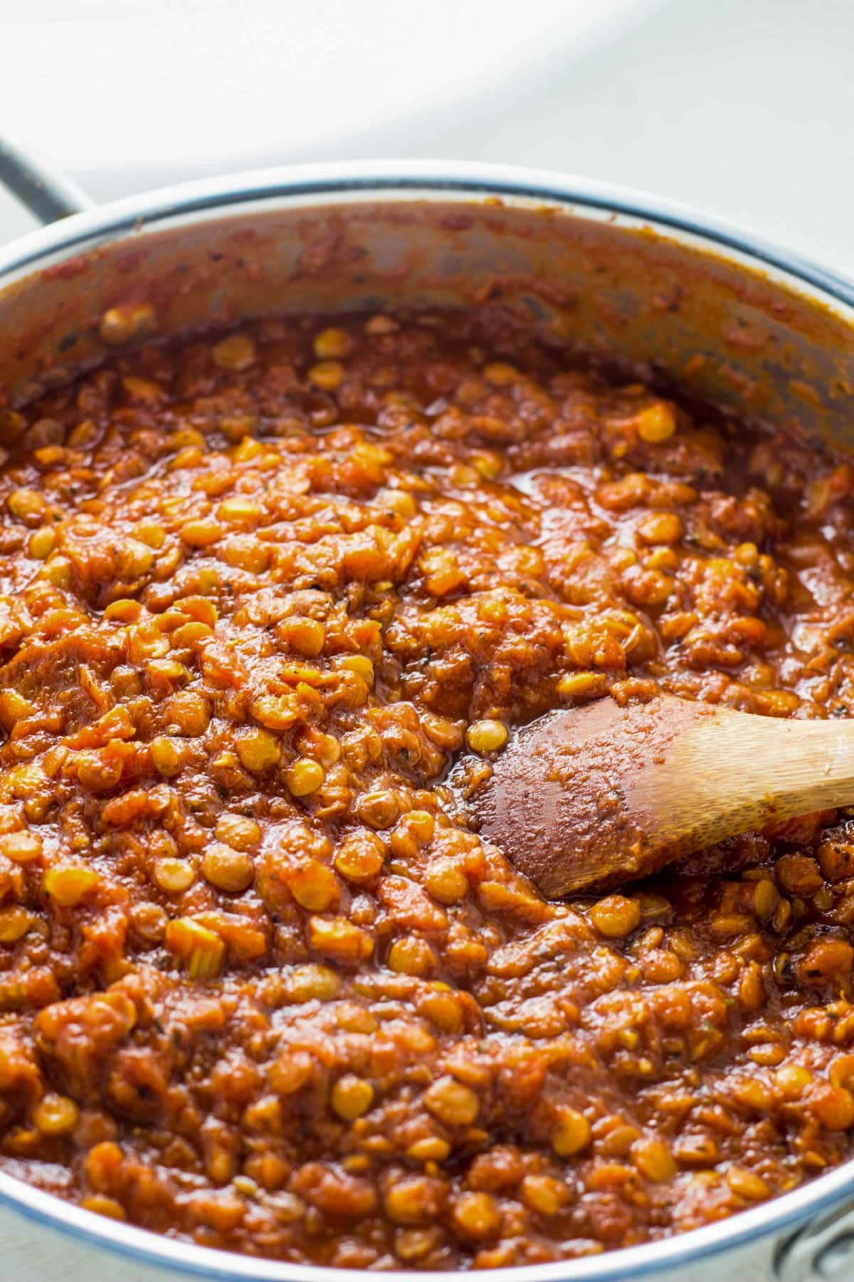 Lentil Bolognese in a sauté pan with a wooden spoon.