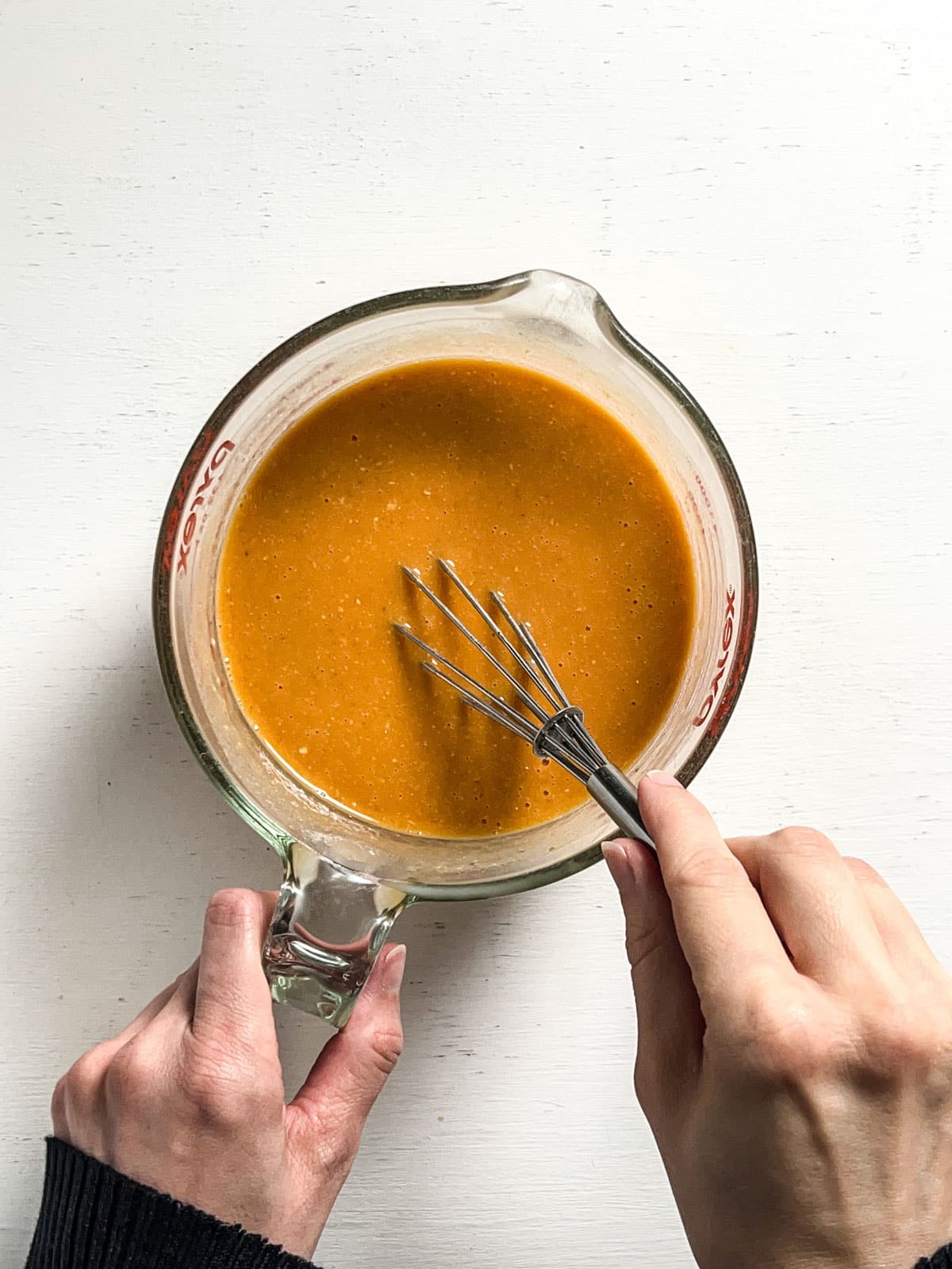 Overhead view of a measuring cup with the wet ingredients to make Pumpkin Cinnamon Swirl Quick Bread.