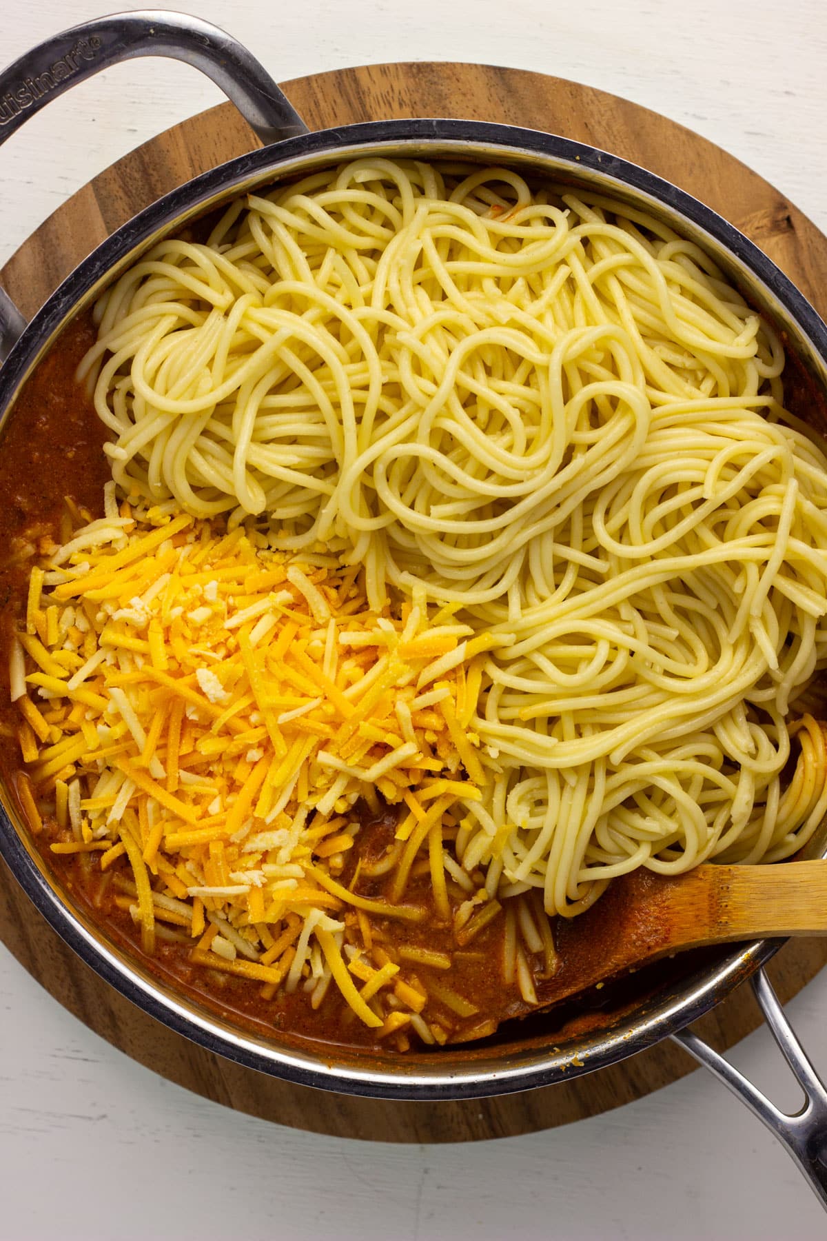 Overhead view of a pan of sauce, spaghetti and vegan cheese before mixing to combine to make Vegan Taco Spaghetti.