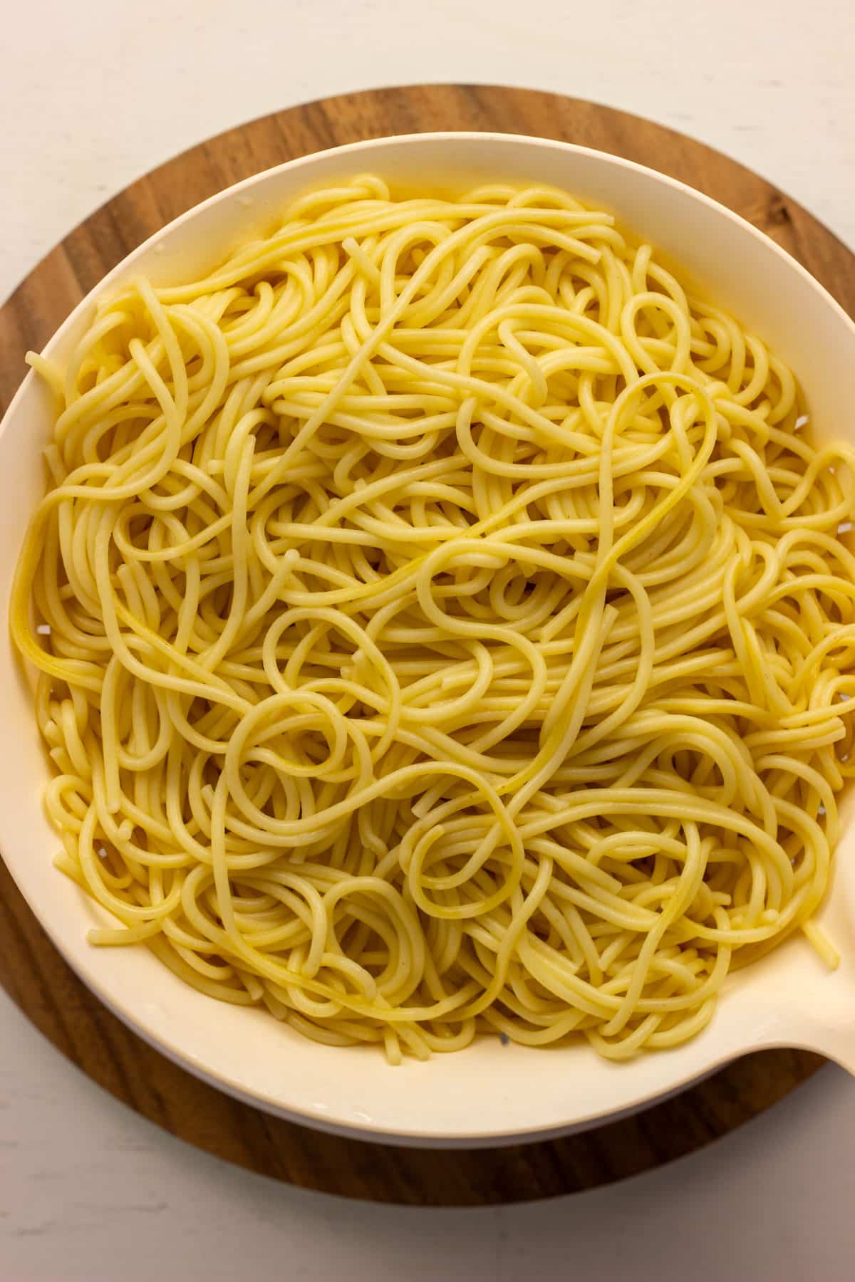 Overhead view of a strainer of cooked spaghetti.