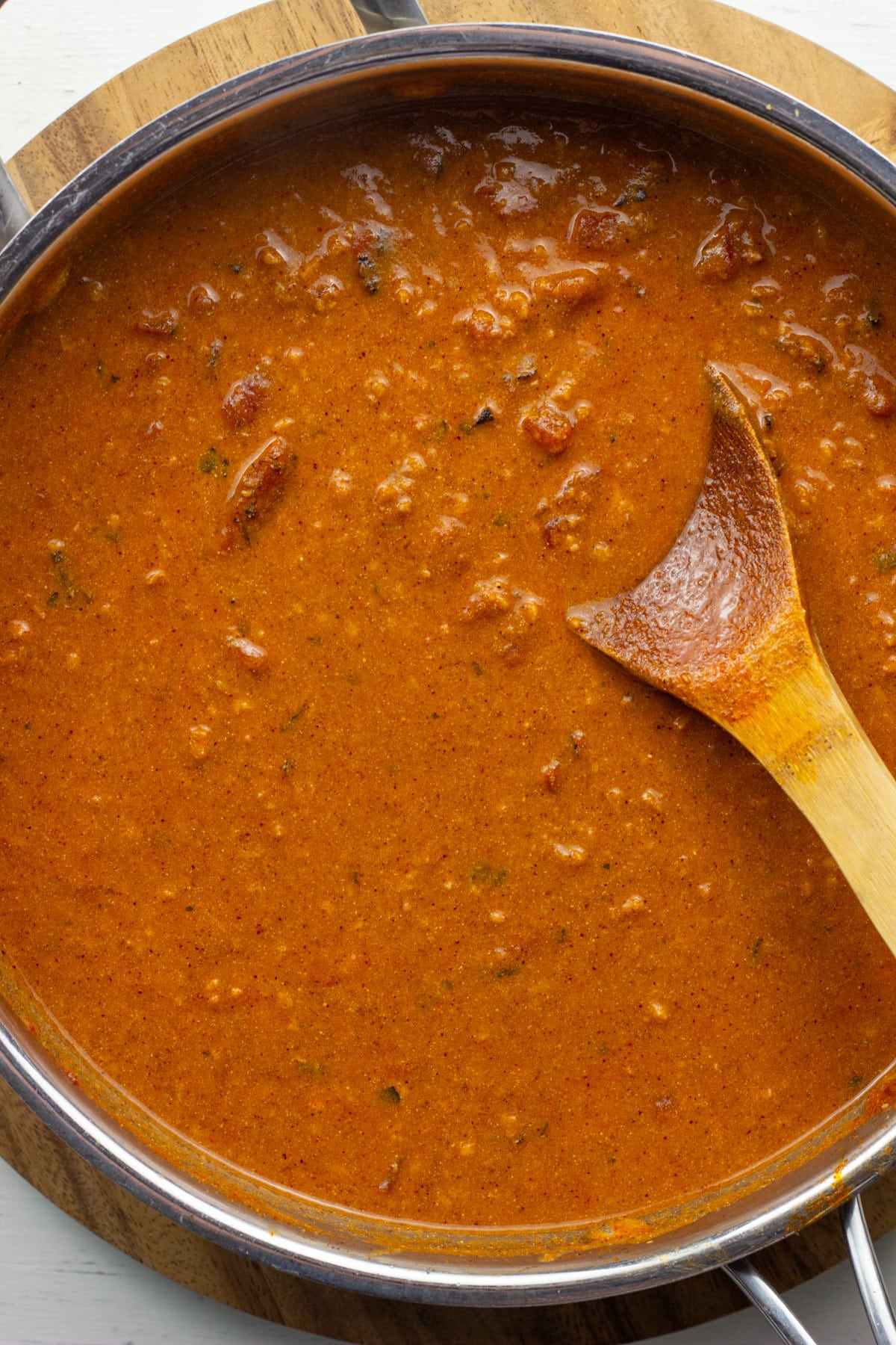 A skillet of sauce for Vegan Taco Spaghetti. There is a wooden spoon in the right side of the pan.