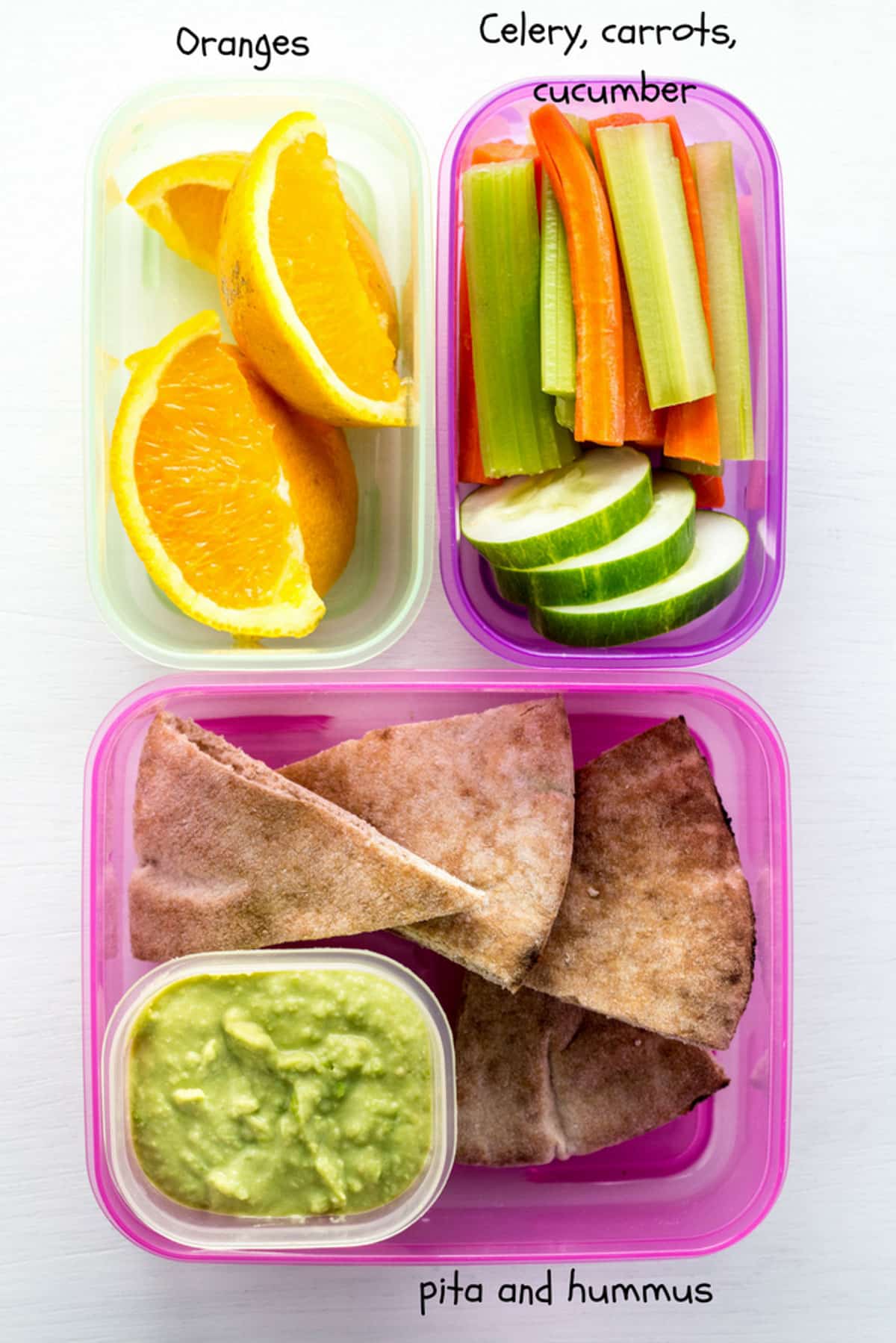 A small green container with orange slices, a small purple container with carrot, celery and cucumber slices and a larger pink container with pita and green hummus. This image is part of What My Vegan Kids Take for School lunch.