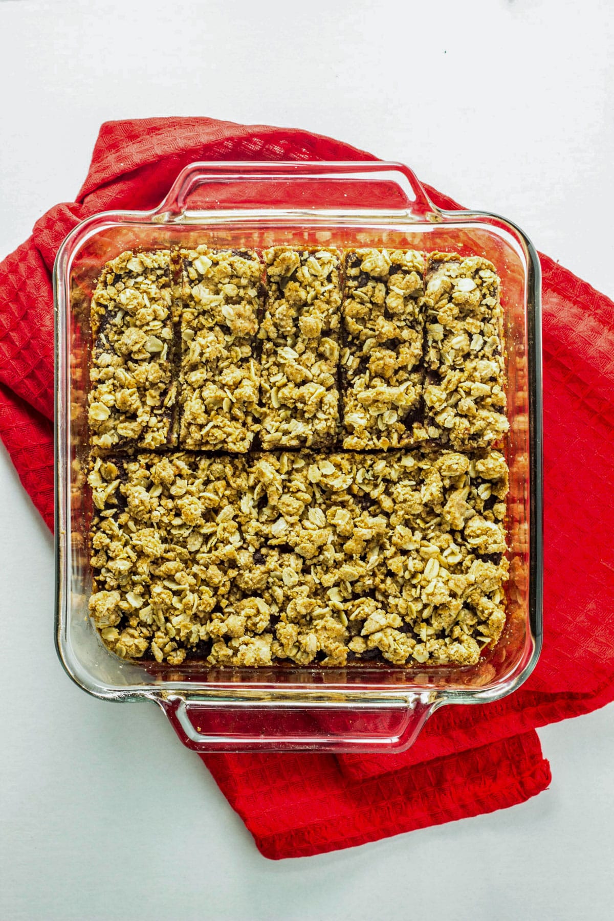 Overhead view of a baking dish of Vegan Apple Butter Oatmeal Bars. The dish sits on a red towel.