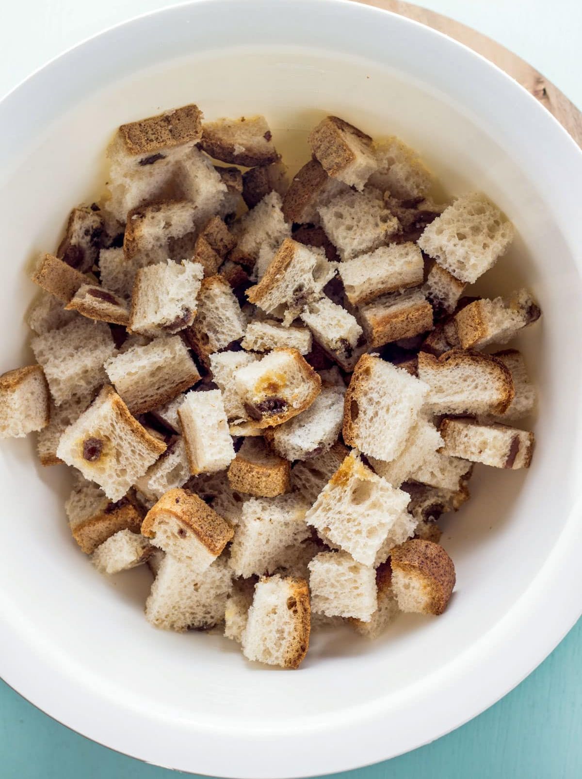 Overhead view of cubed cinnamon and raisin bread in a bowl.