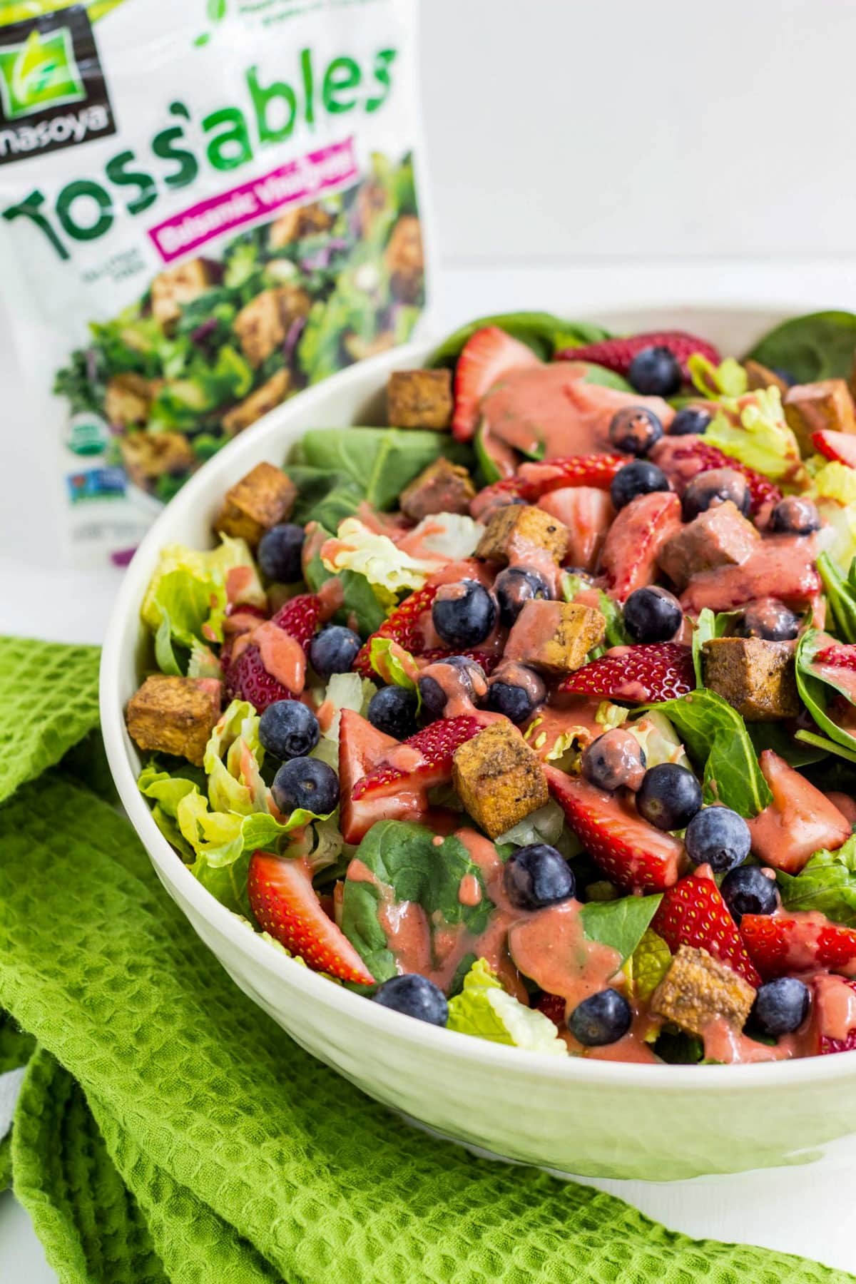 Fruity Balsamic Tofu Salad in a large. There is a green towel next to the bowl and a package of tofu in the background.