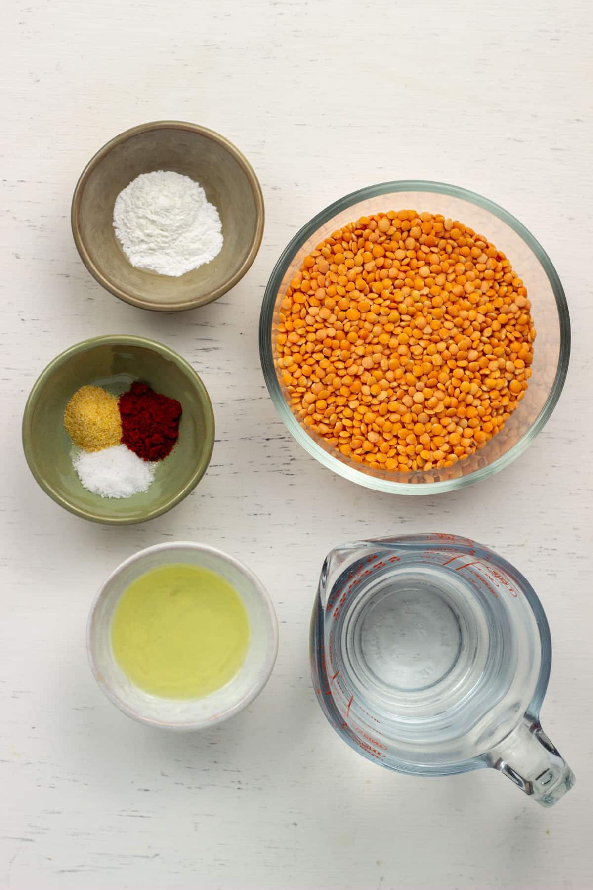 Ingredients to make Smoky Red Lentil Crackers including a bowl of red lentils, water, oil, baking powder, garlic powder, smoked paprika and salt.