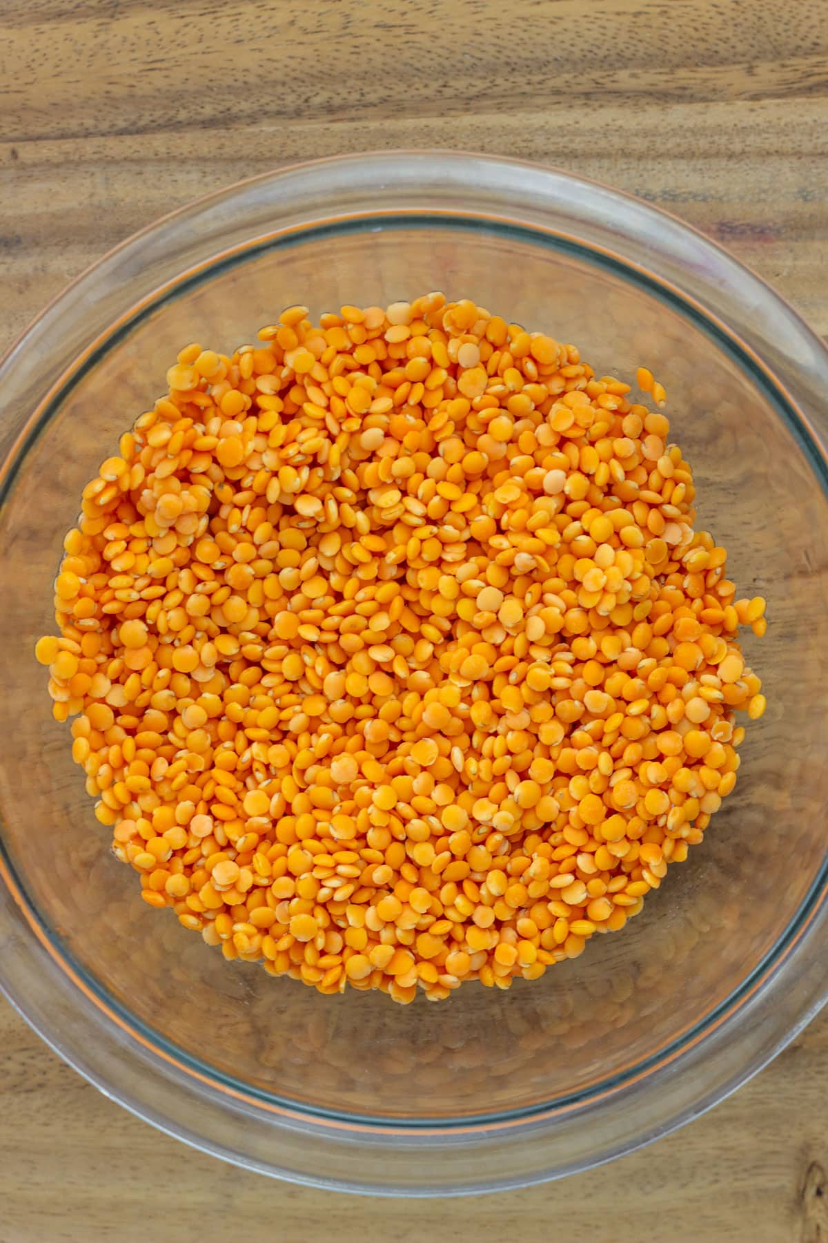 Overhead view of a glass bowl of red lentils.
