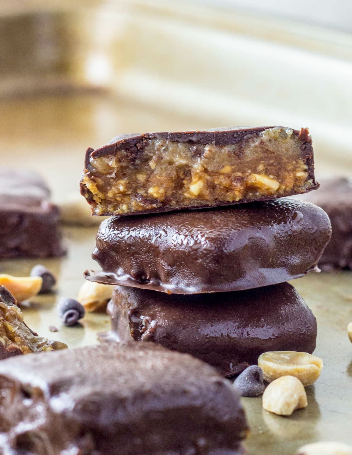 A stack of Vegan Peanut Butter Snickers Bites. The top bite is cut in half to show the inside.