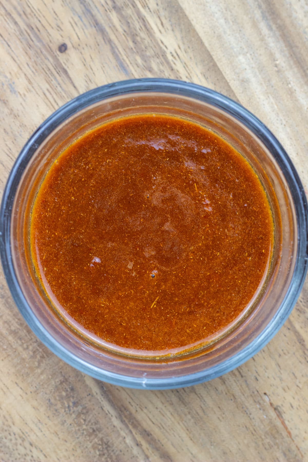 A bowl of chipotle sauce sitting on a wooden board.