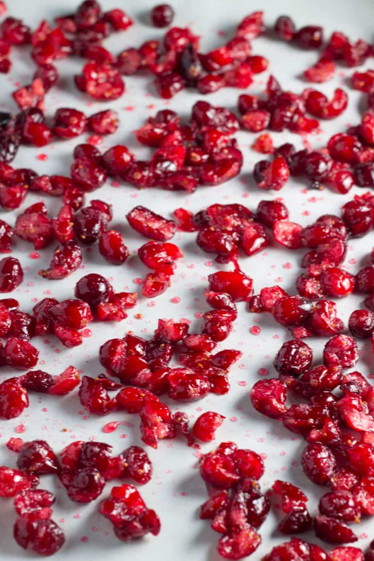 Chopped fresh cranberries coated in sugar on a baking sheet. The cranberries will be baked until dried.