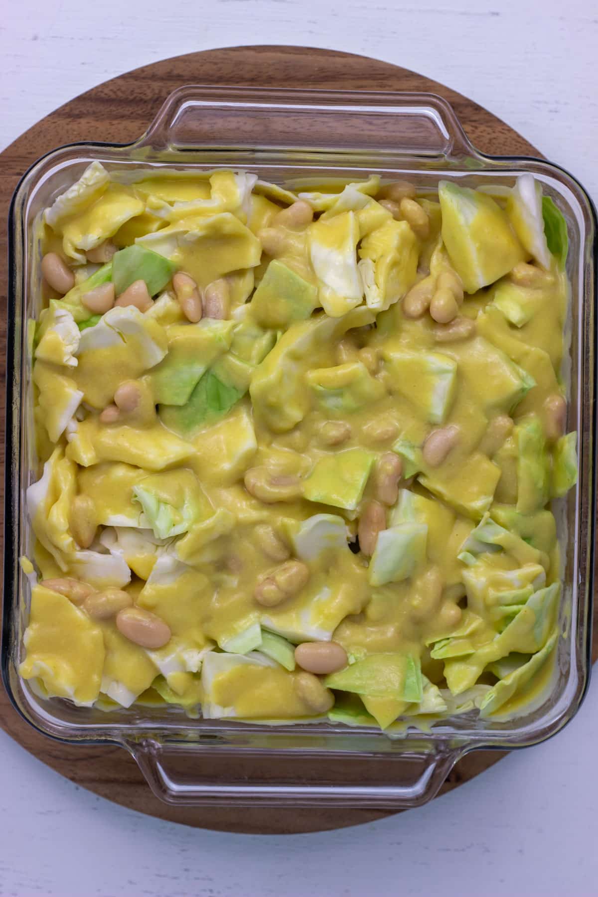 Overhead view of chopped cabbage and cannellini beans with sauce poured over.
