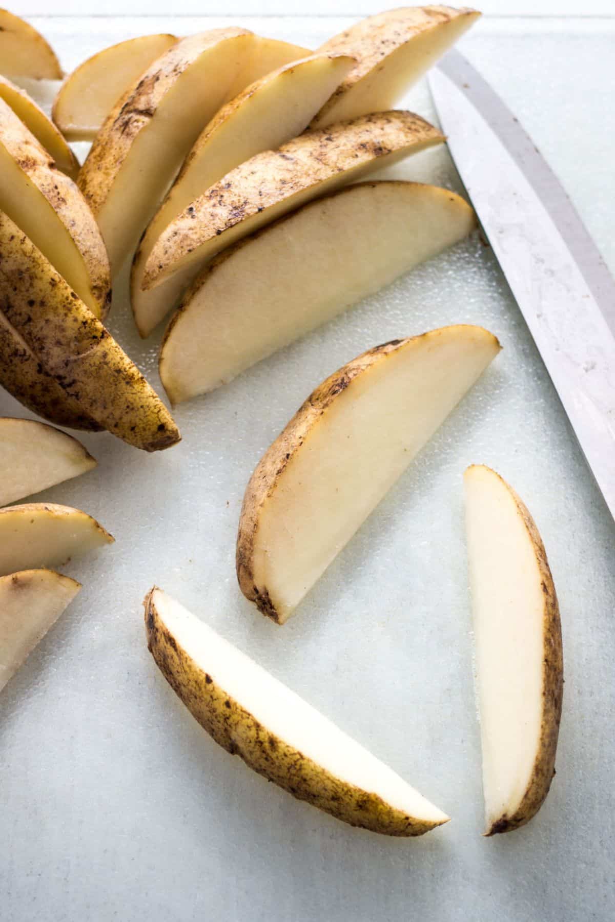 Potatoes that have been cut into wedges to make Vegan Cheesy Herb Potatoes.