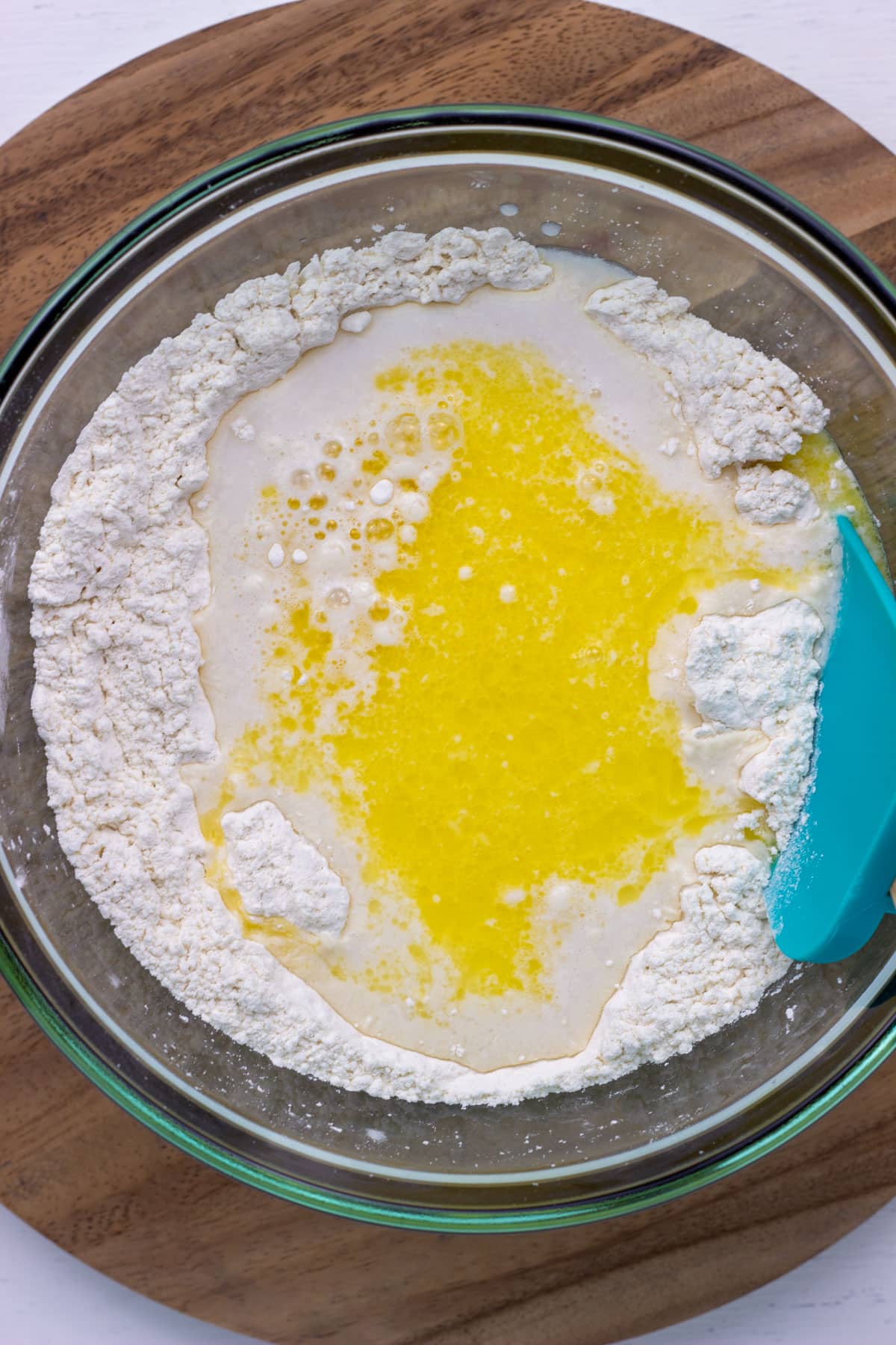 Overhead view of a green bowl with flour, non dairy milk and non dairy butter before mixing together.