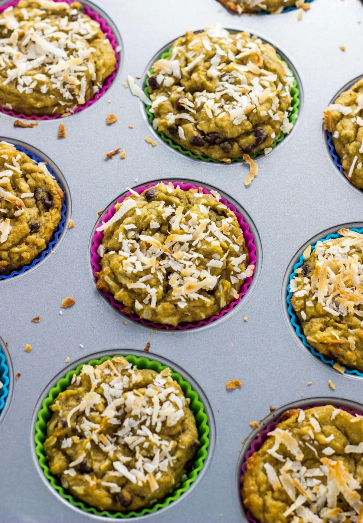 Freshly baked Coconut Chocolate Chip Banana Muffins with toasted coconut on top still in the muffin pan.